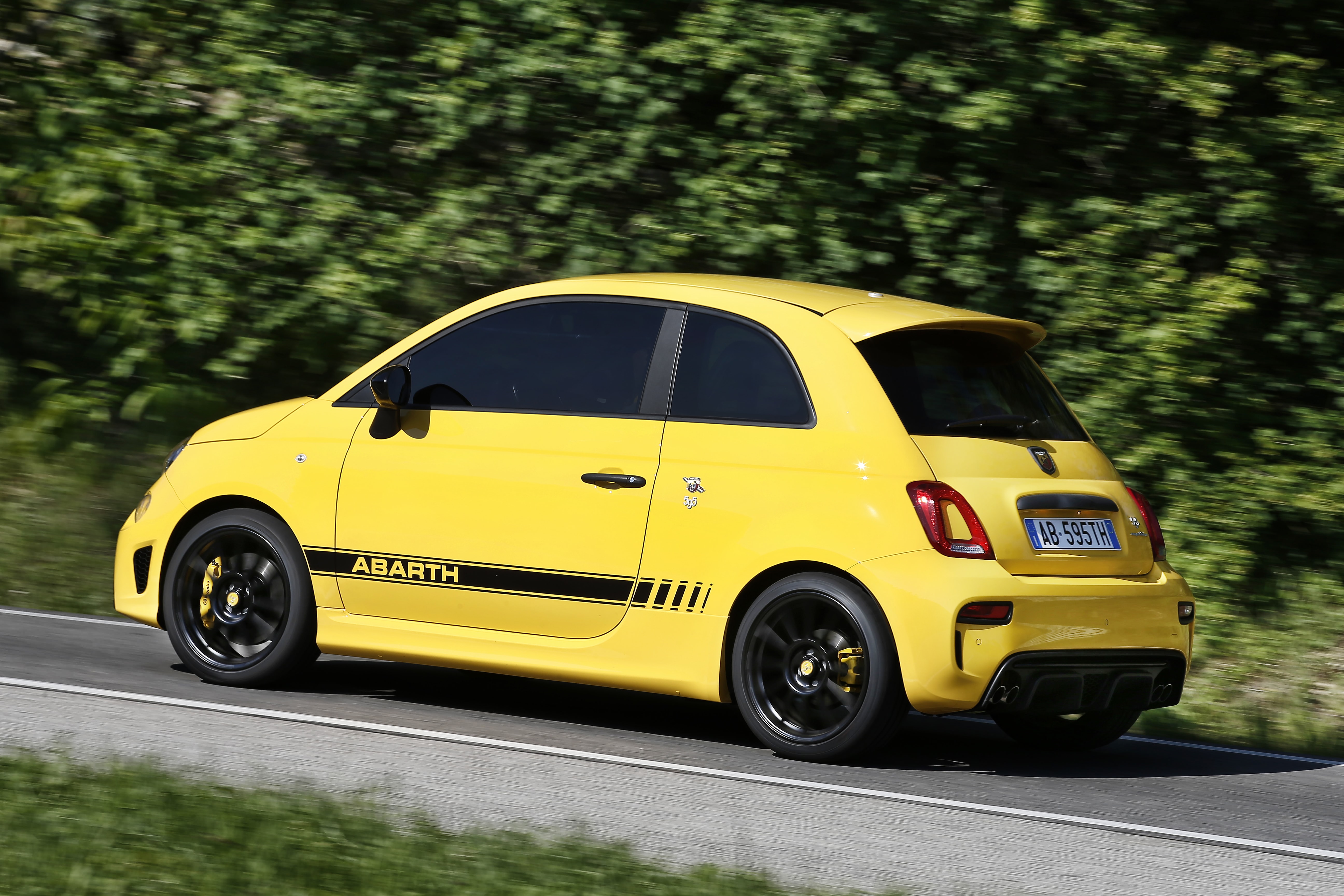 Abarth 500 amarillo en carretera con un paisaje impresionante al fondo.