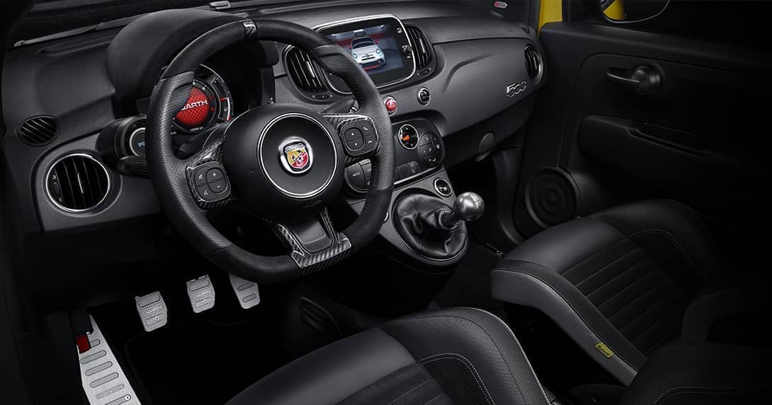 Vista interior del Abarth 500, con asientos deportivos en negro y detalles en rojo.