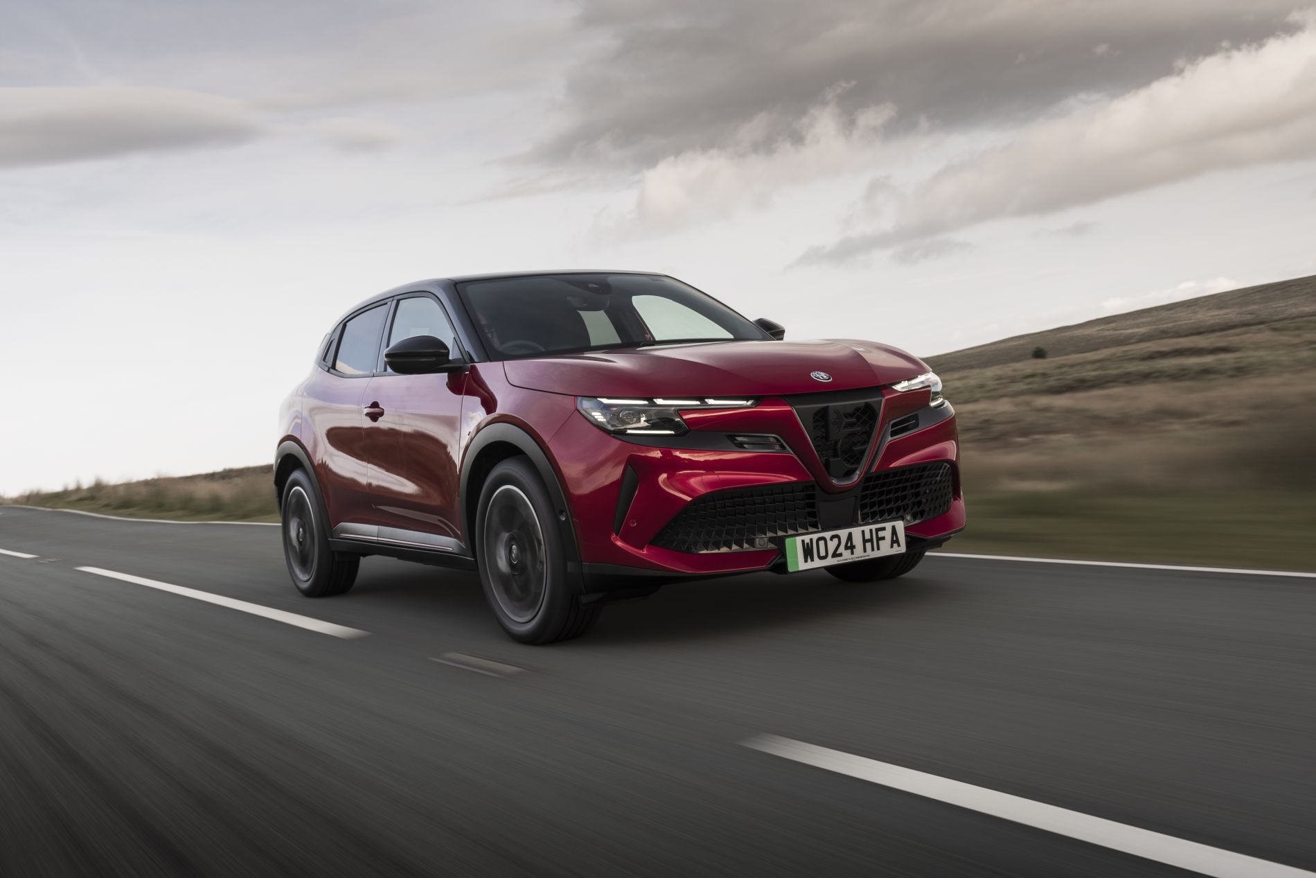 Alfa Romeo Junior eléctrico en un entorno campestre, elegante en movimiento.