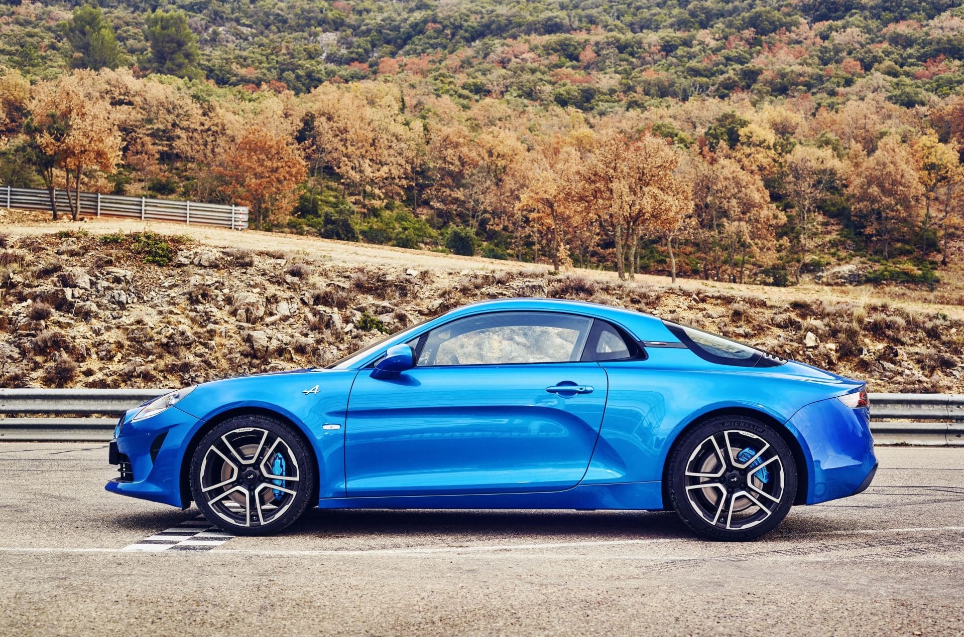 Perfil del Alpine A110 del lado del conductor con paisaje de fondo.