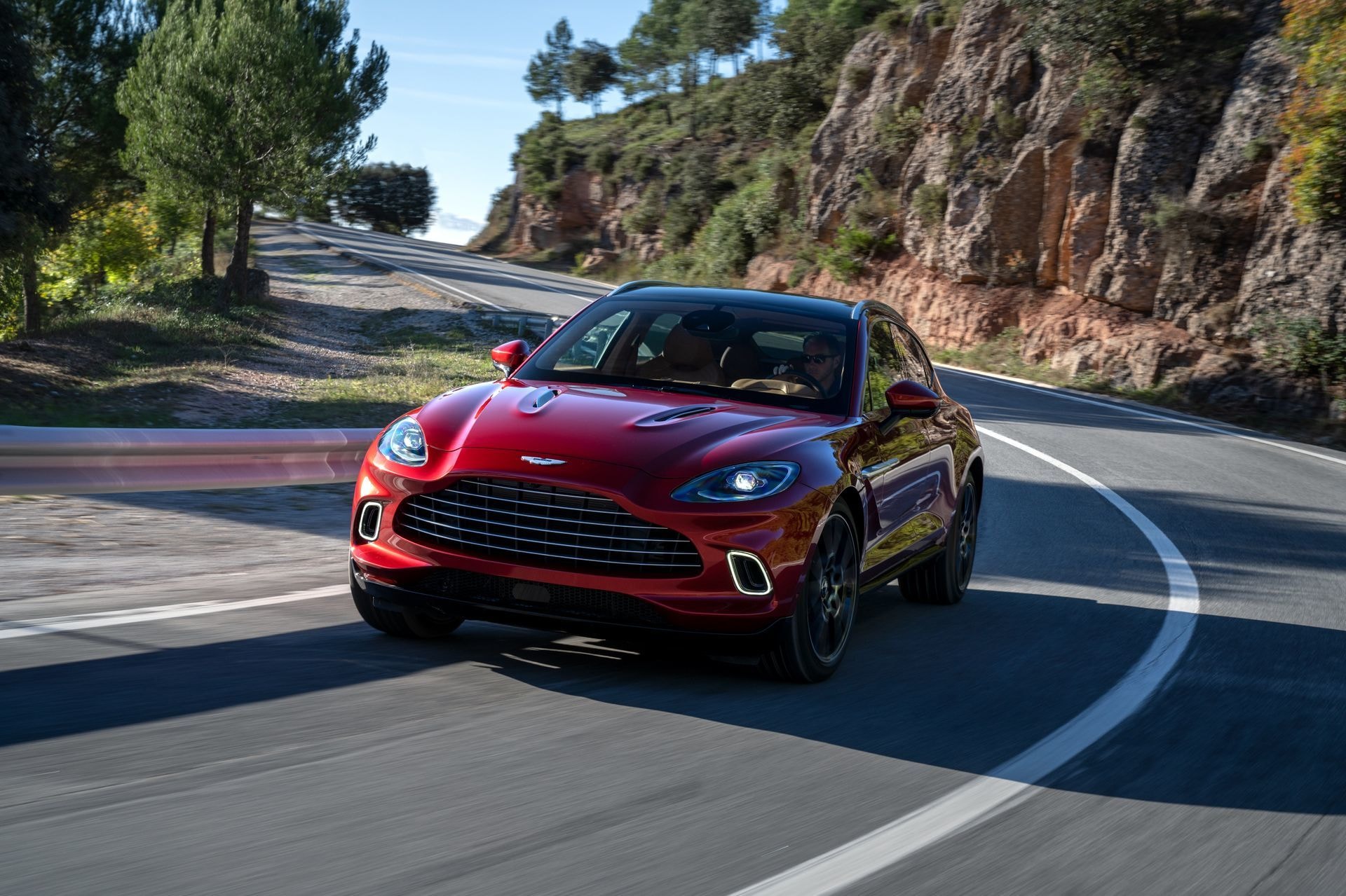 Aston Martin DBX abriéndose paso con elegancia por una curva.