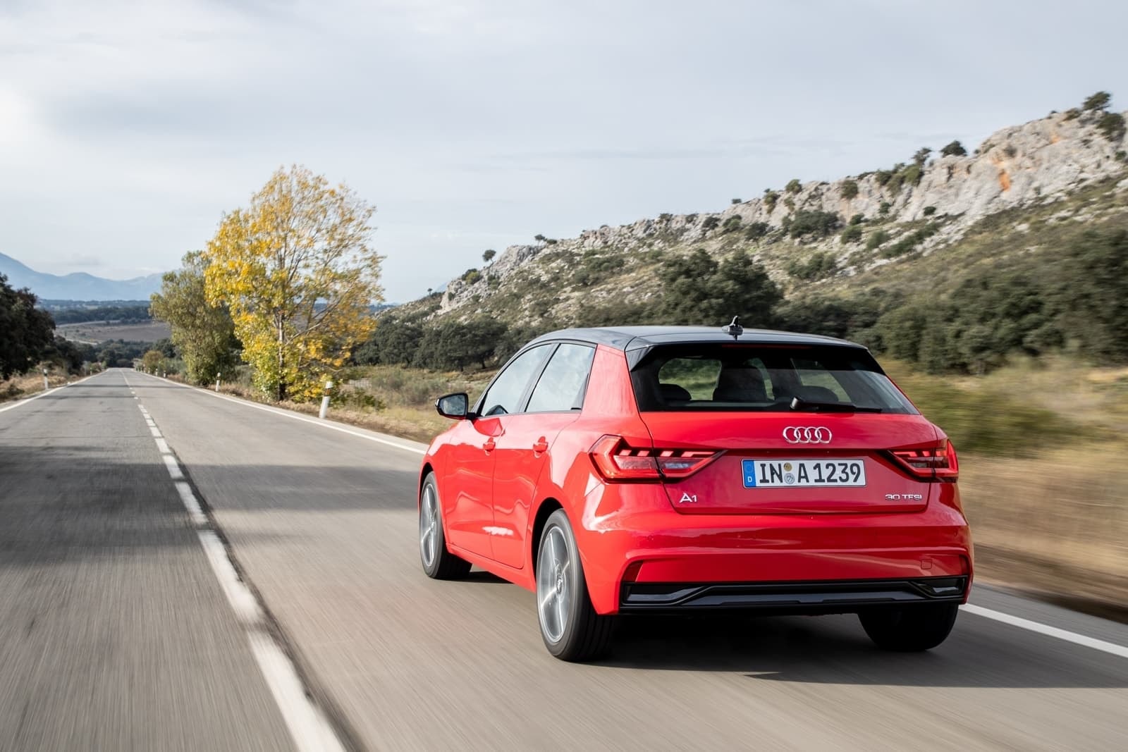 Vista dinámica del Audi A1 en color rojo, enfoque en la parte trasera y lateral.