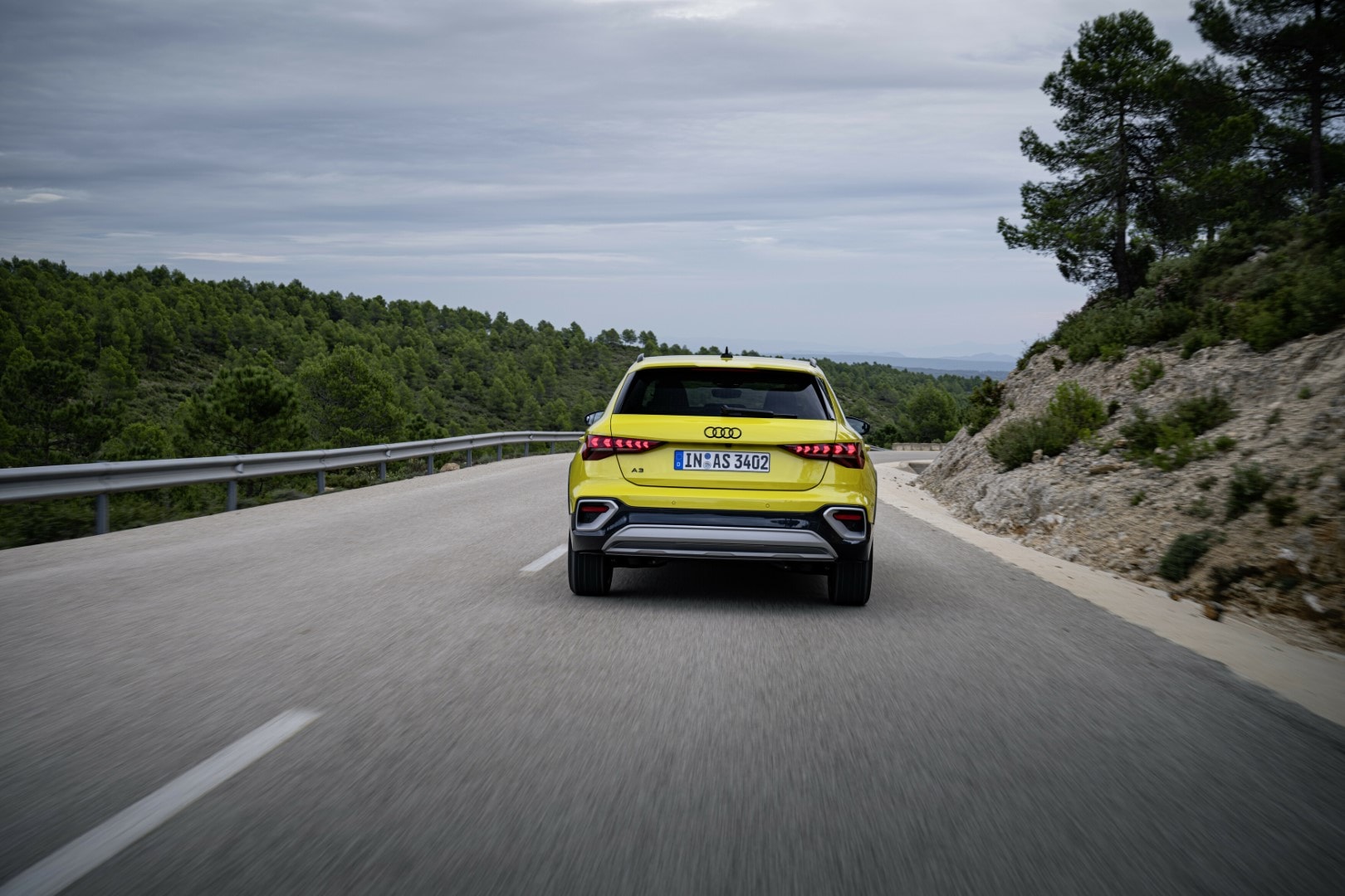 Muestra la parte trasera del Audi A3 en movimiento, destacando sus luces y diseño aerodinámico.