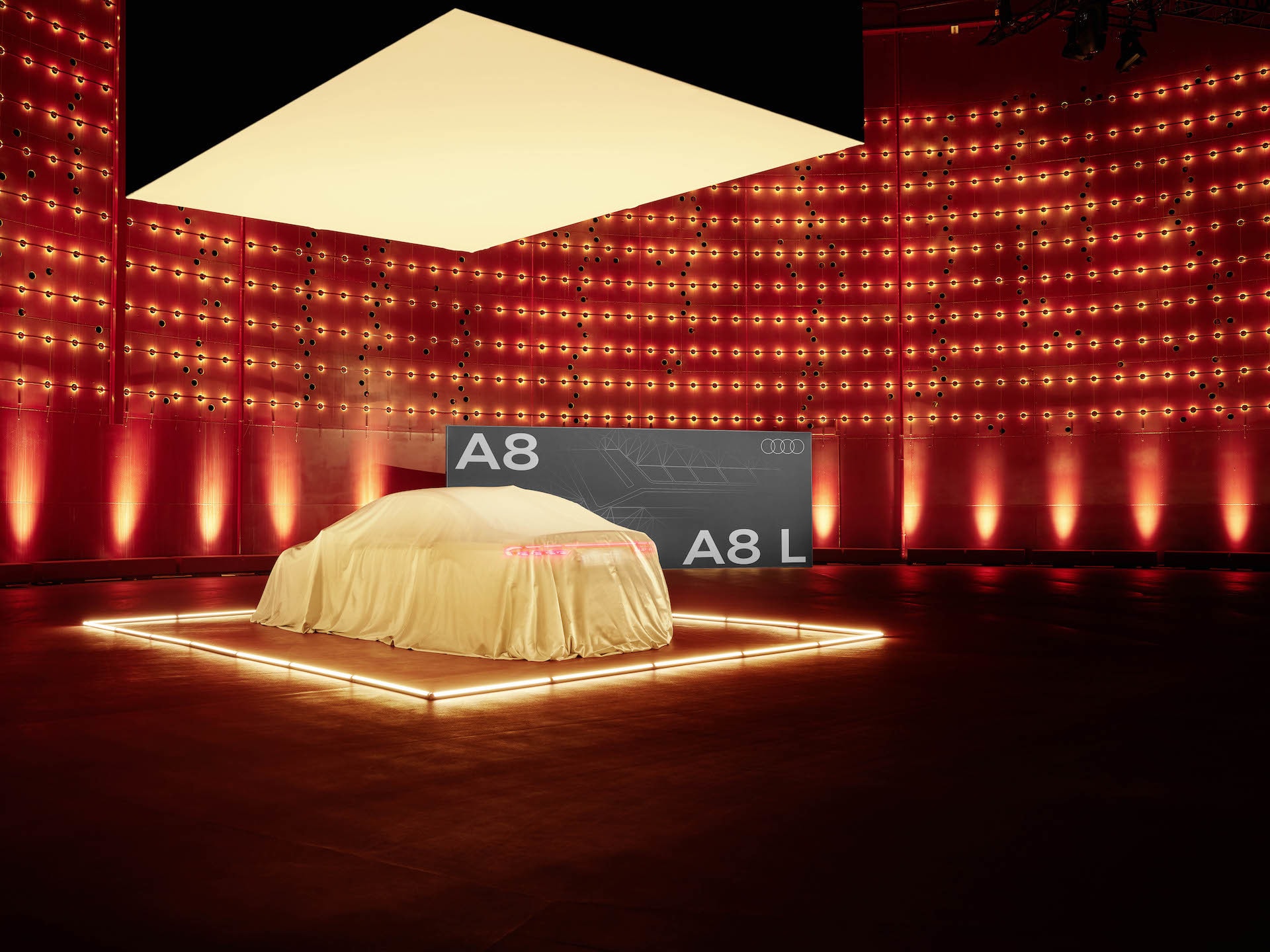 Audi A8 esperando su revelación bajo una lona iluminada.