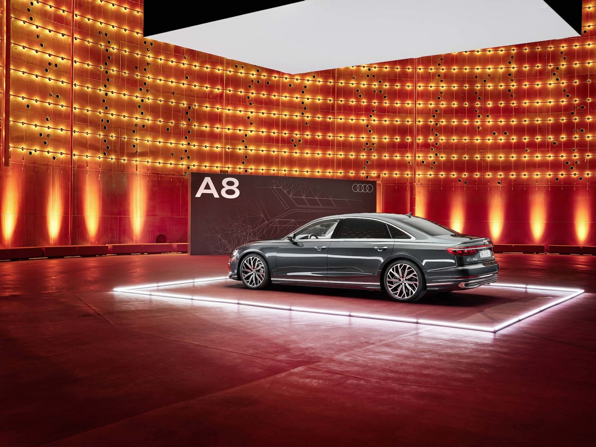 Vista trasera del Audi A8 en un escenario con iluminación dinámica, foco en diseño de luces.