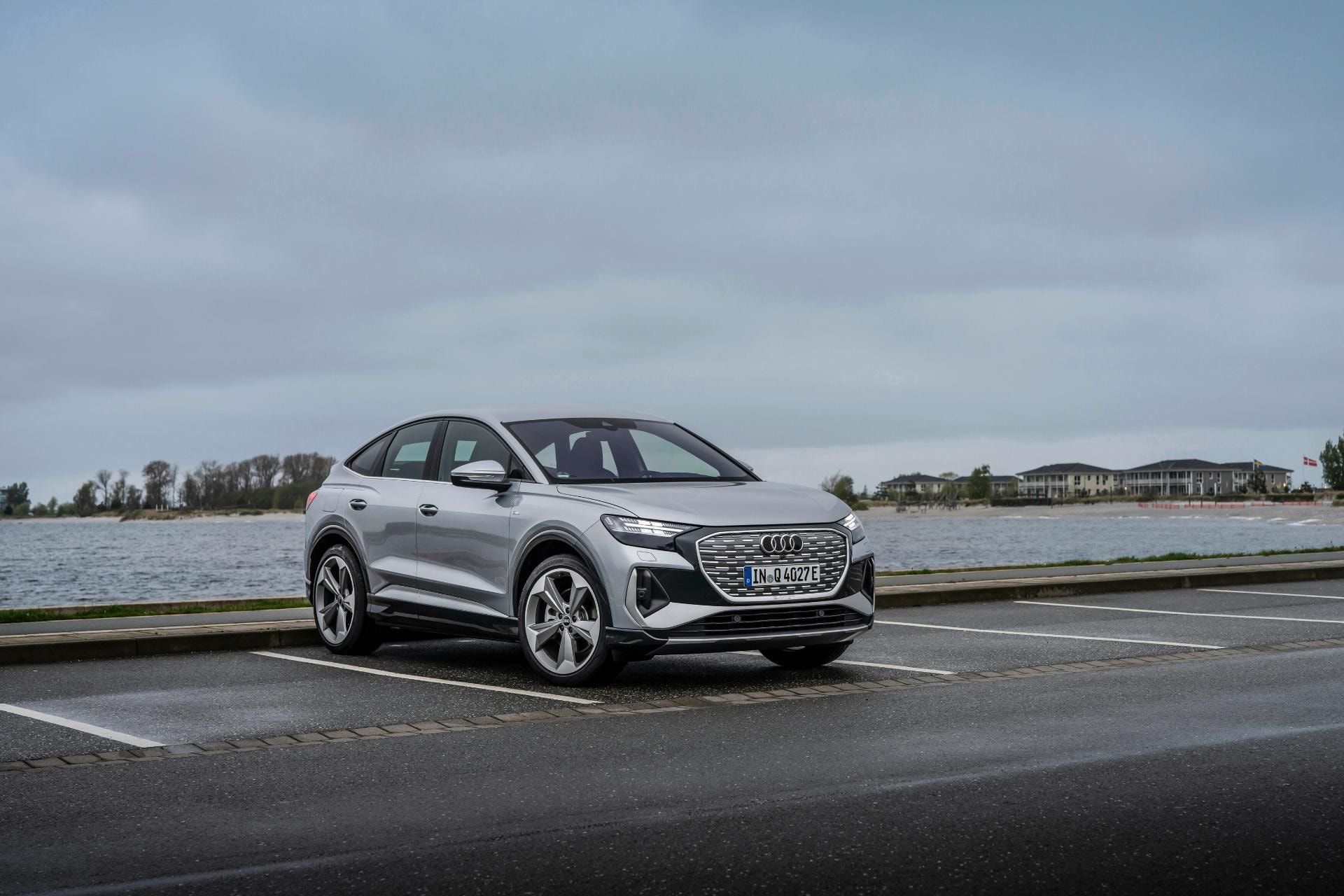 El Audi Q4 e-tron capturado en una toma lateral con un paisaje acuático sereno