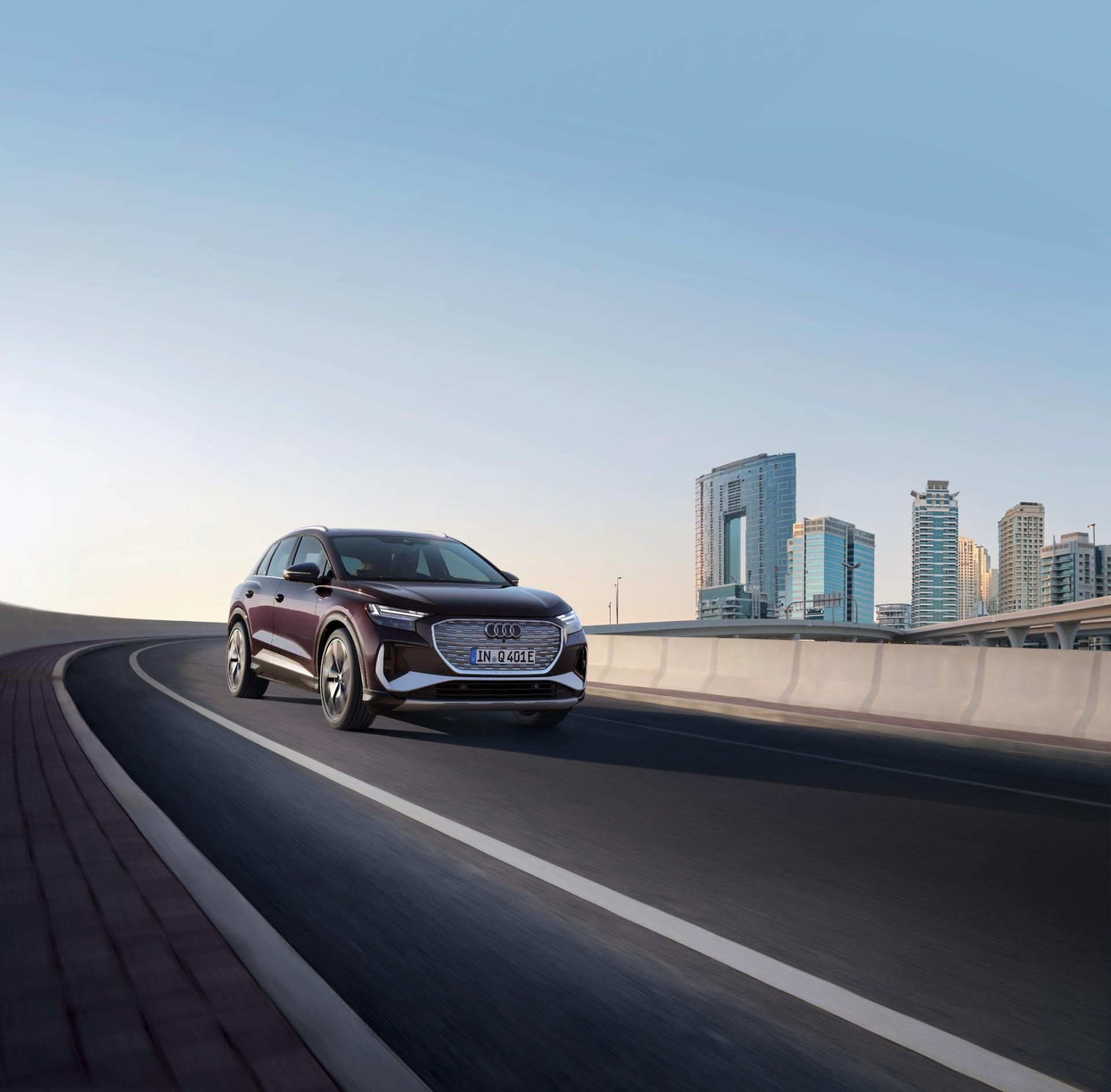 Imagen dinámica del Audi Q4 e-tron cruzando un puente con skyline urbano