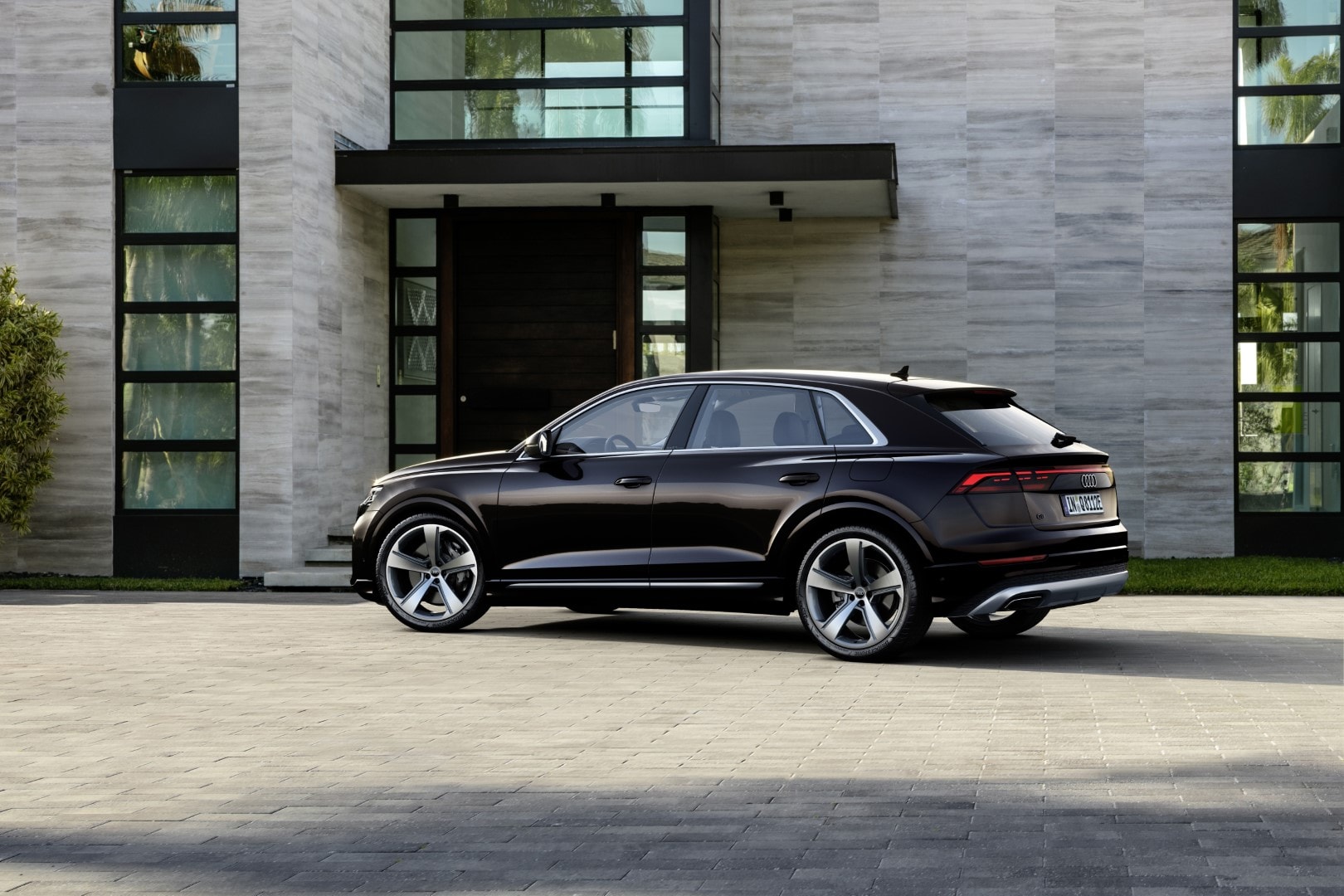 Perfil trasero del Audi Q8 Híbrido ante una residencia moderna.