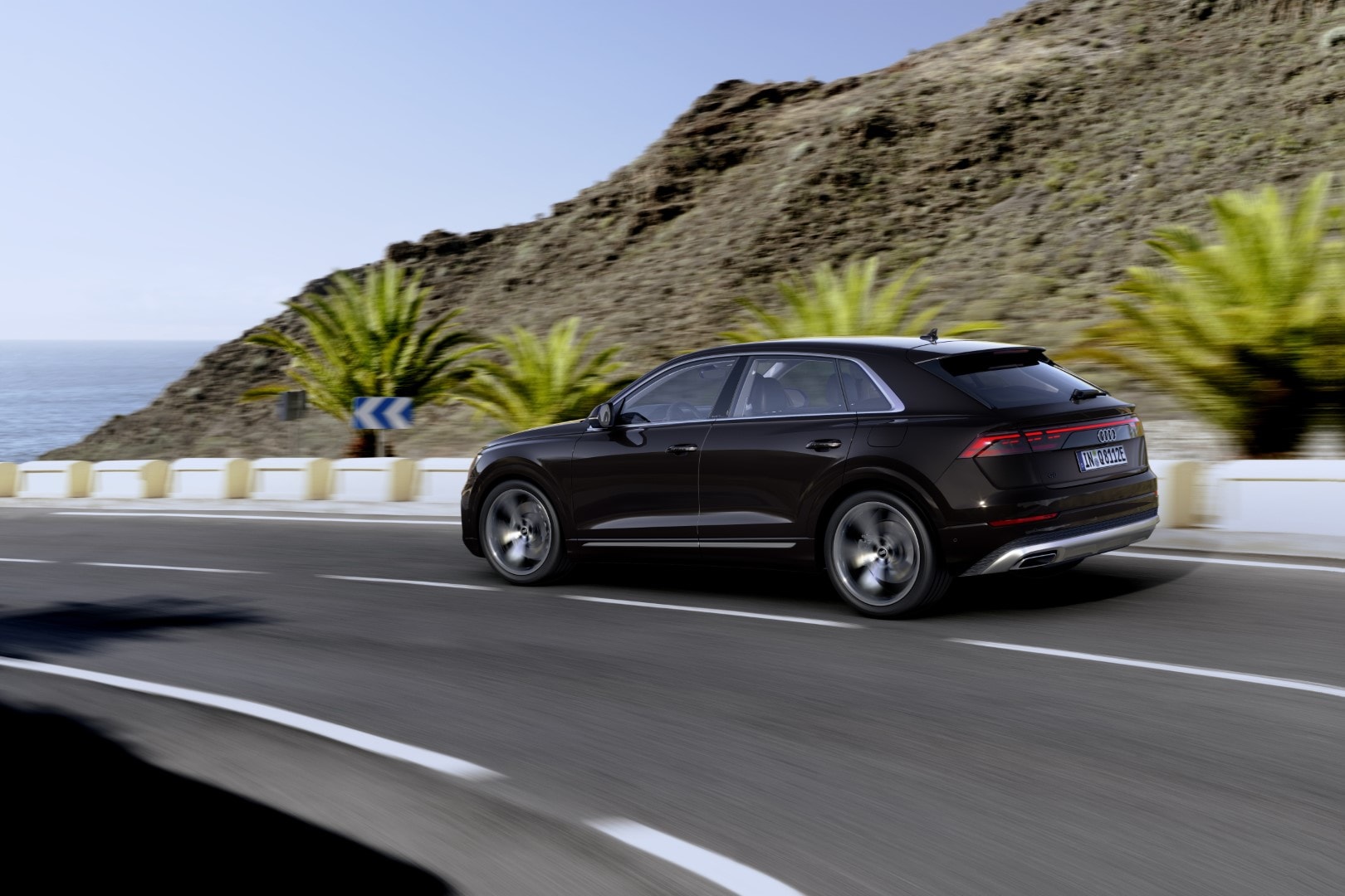 Vista lateral trasera del Audi Q8 Híbrido en marcha, mostrando su aerodinámica y deportividad.