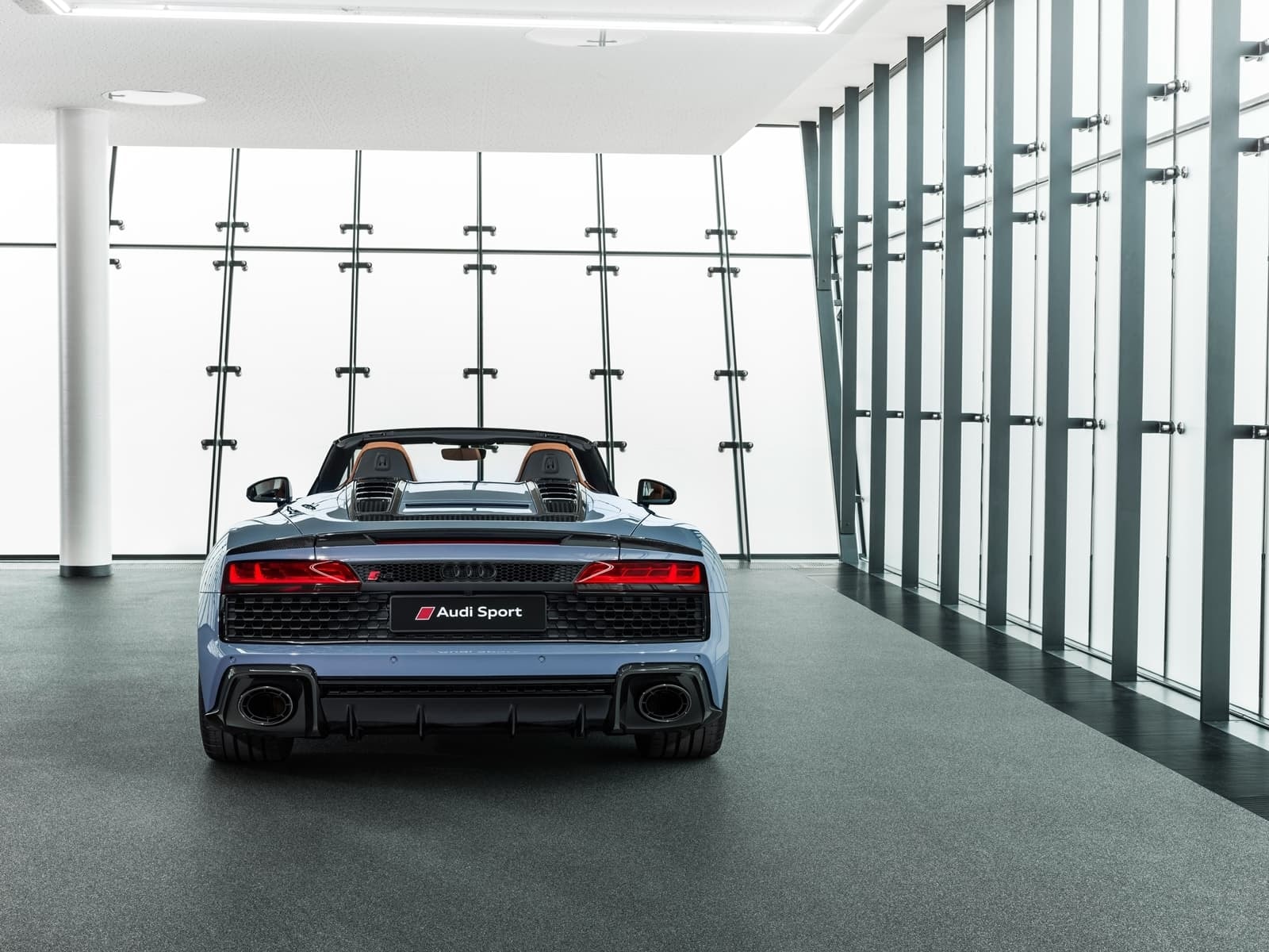 Imagen trasera del Audi R8 Spyder con la capota bajada, resaltando la deportividad.