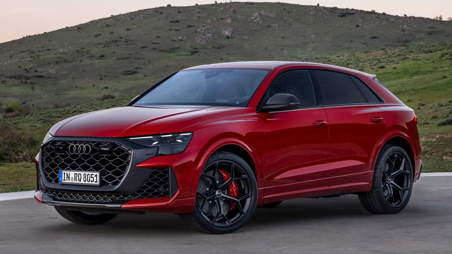 Vista lateral y frontal del Audi RS Q8 en rojo, mostrando su diseño deportivo y robusto.