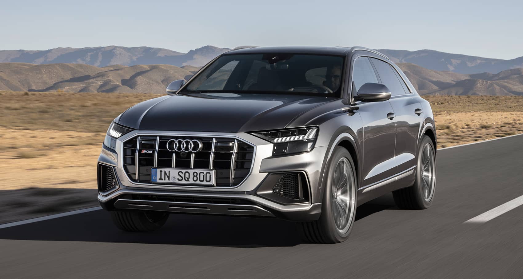 Audi SQ8 en movimiento, mostrando su imponente vista delantera.