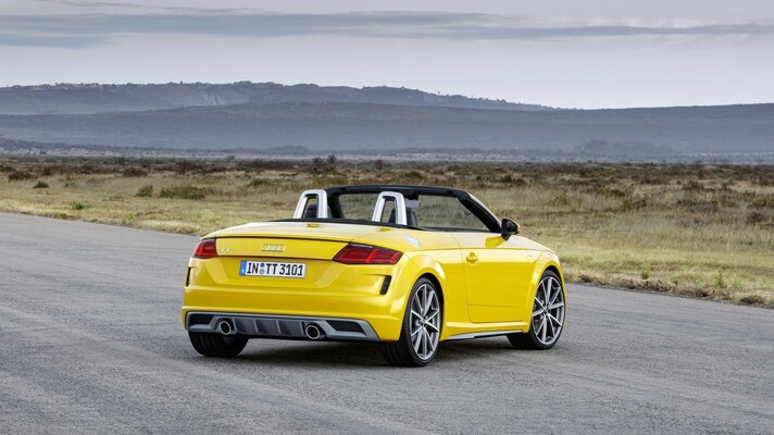 Vista lateral completa del Audi TT Roadster en color amarillo vibrante y capota bajada. Vista lateral completa del Audi TT Roadster en color amarillo vibrante y capota bajada.