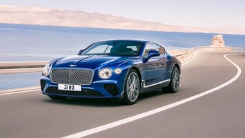 Bentley Continental GT en azul recorriendo costa soleada. Bentley Continental GT en azul recorriendo costa soleada.