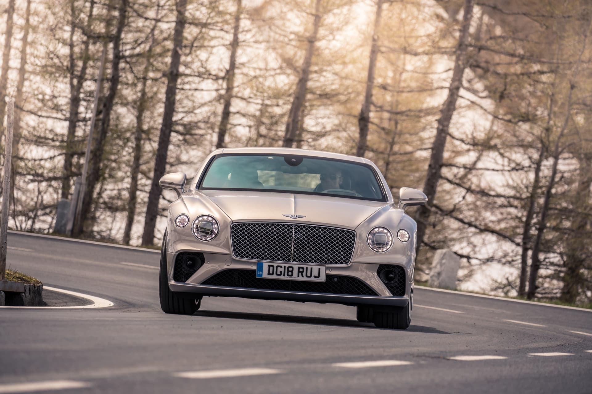 Enfoque frontal del Bentley Continental GT en ruta, reflejando su presencia en carretera.