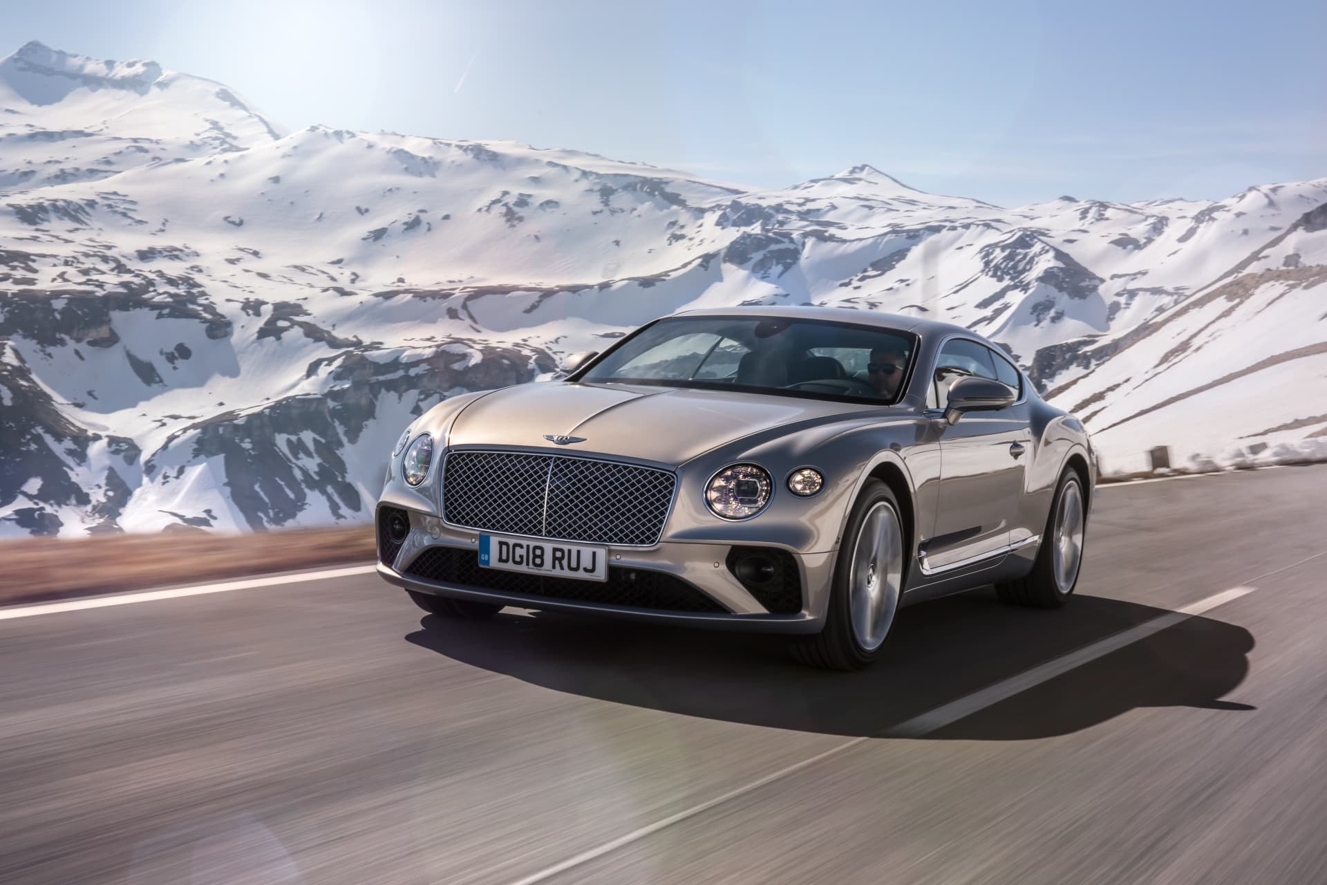 Fotografía en acción del Bentley Continental GT con montañas de fondo.