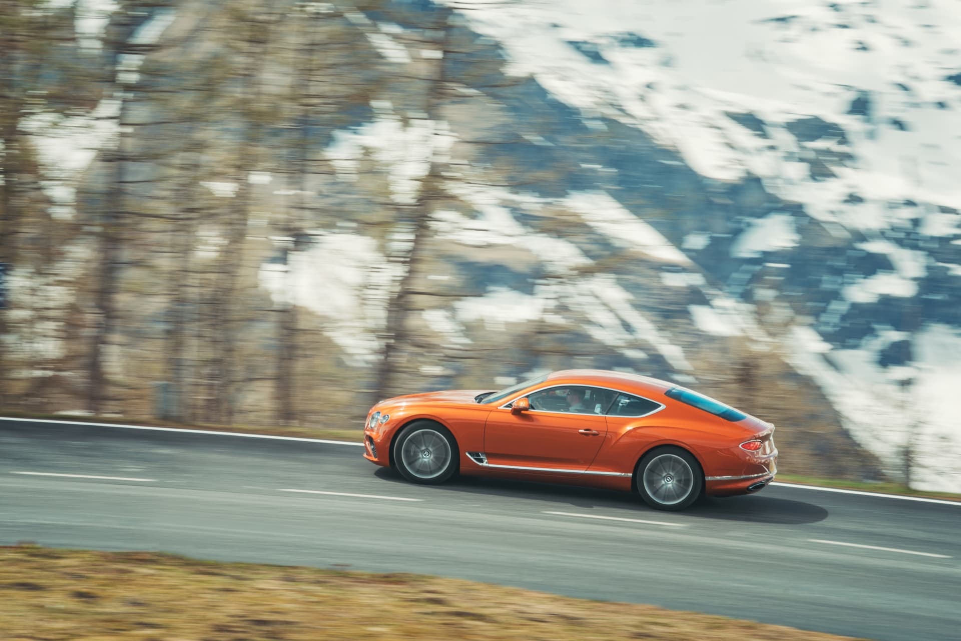 Un perfil imponente del Bentley Continental GT rodando en una carretera rodeada de nieve.