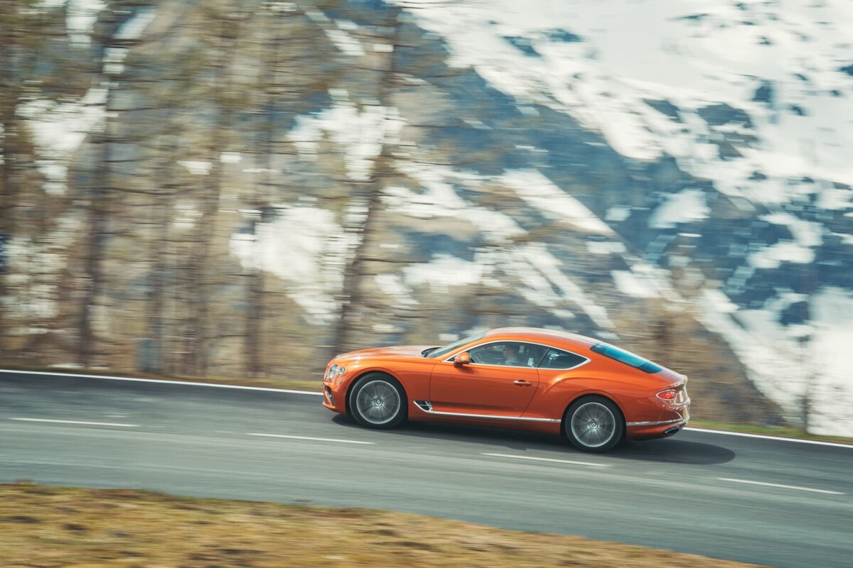 Un perfil imponente del Bentley Continental GT rodando en una carretera rodeada de nieve. Un perfil imponente del Bentley Continental GT rodando en una carretera rodeada de nieve.