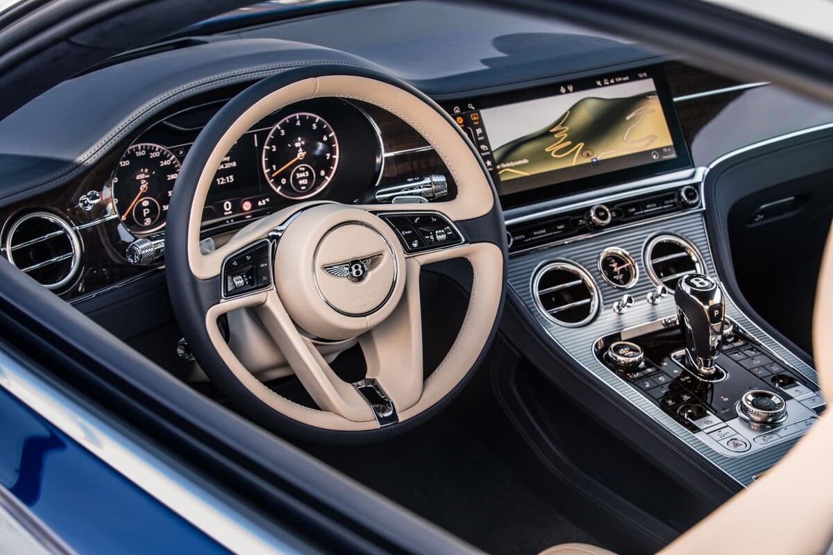 Cabina lujosa del Bentley Continental GT con volante y pantalla central. Cabina lujosa del Bentley Continental GT con volante y pantalla central.
