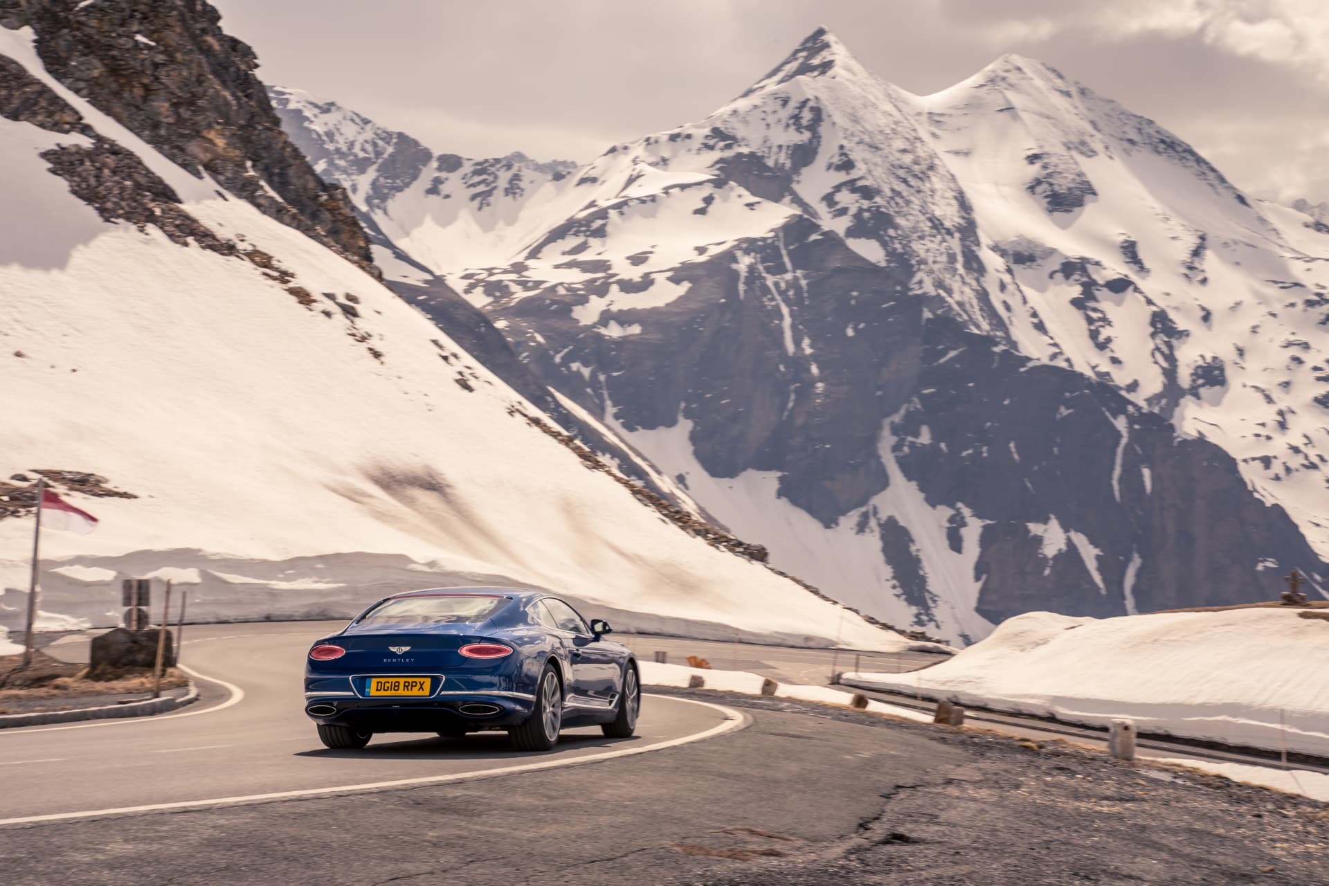 Un espectacular Bentley Continental GT con montañas nevadas de fondo.