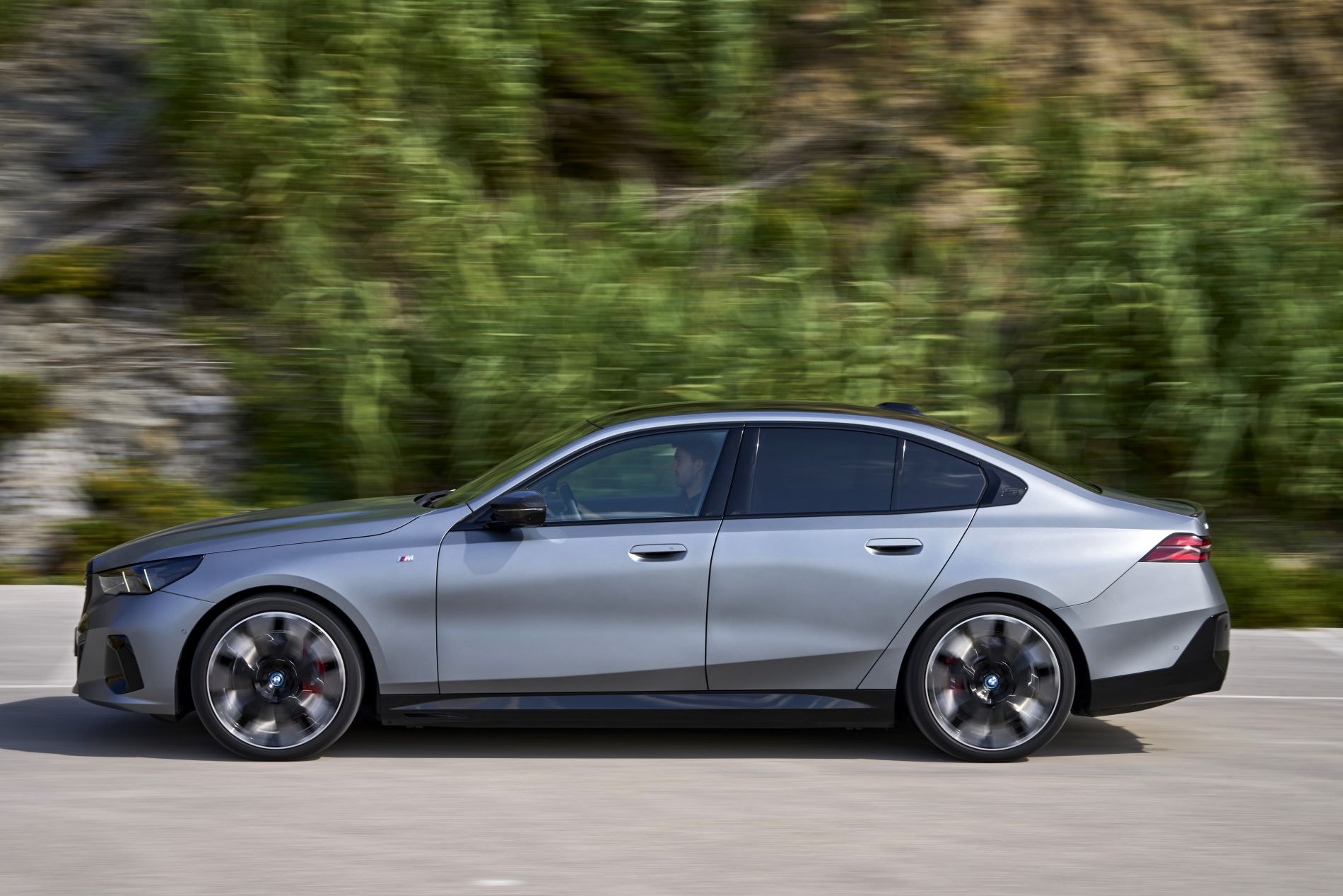 Mirada lateral del BMW i5 que resalta su elegancia en un entorno natural.