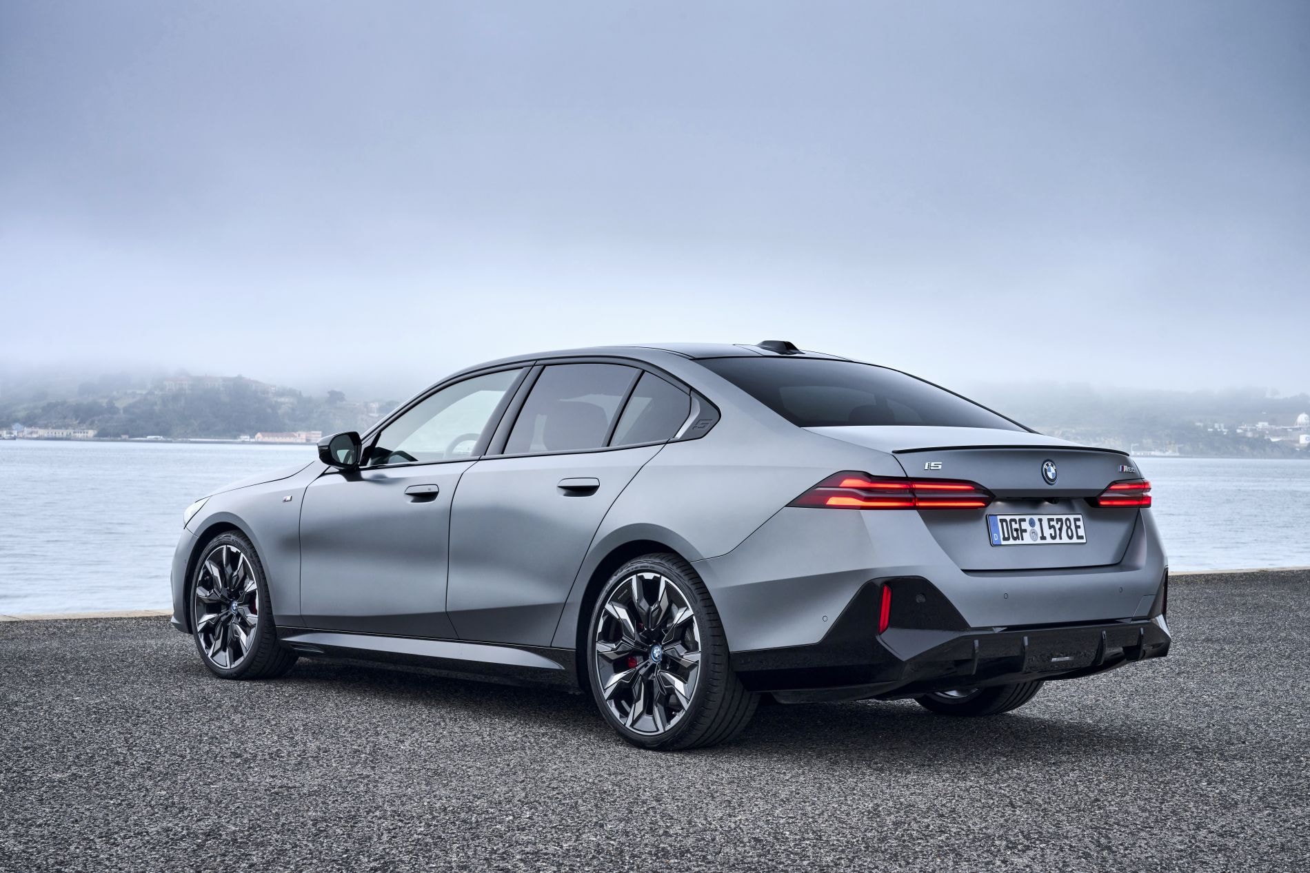 Perfil trasero del BMW i5 junto al mar, resaltando su estética moderna.