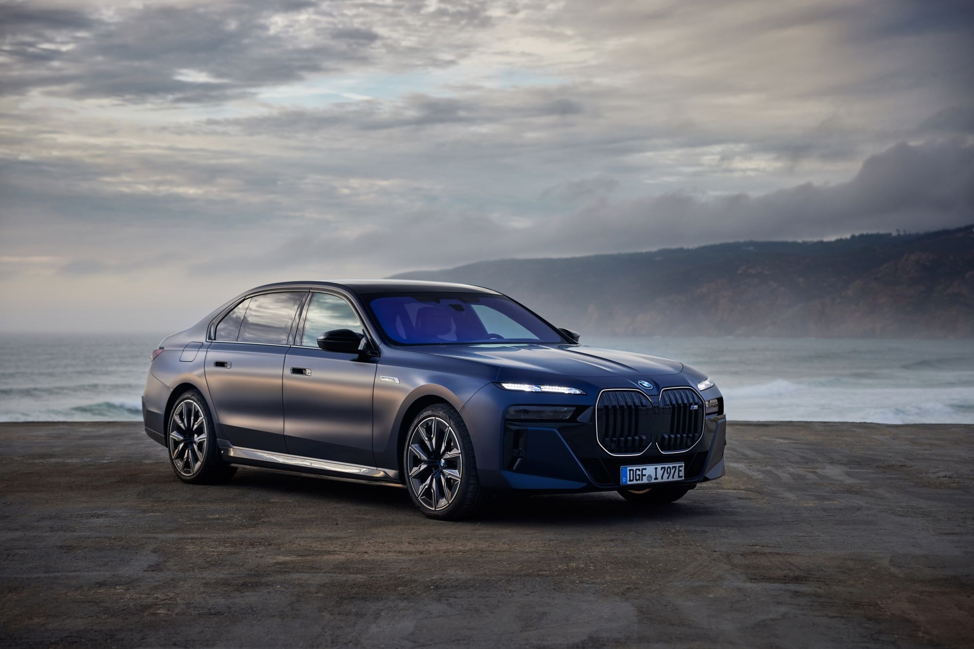 Vista trasera del BMW i7, con un fondo de playa impresionante.