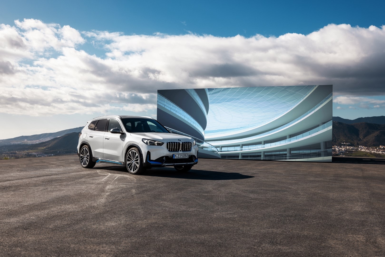 BMW iX1 eléctrico presentado frente a una edificación moderna con cielo despejado.