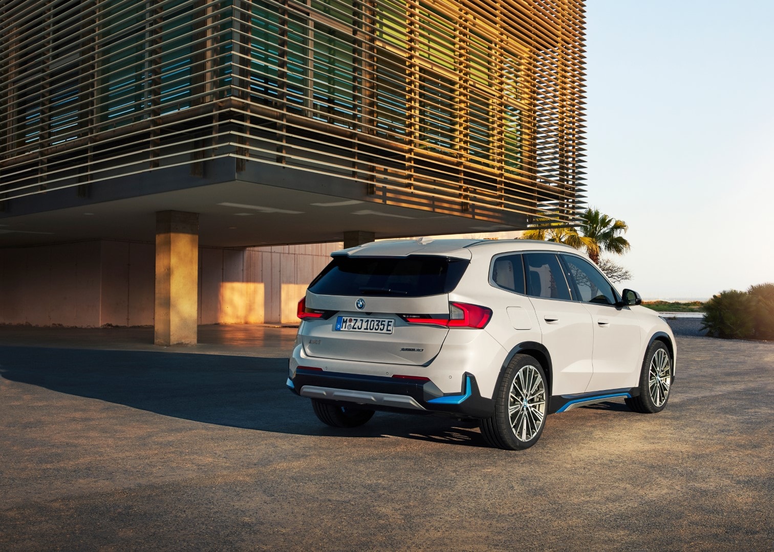 Trasera del BMW iX1 eléctrico con un edificio moderno de fondo.