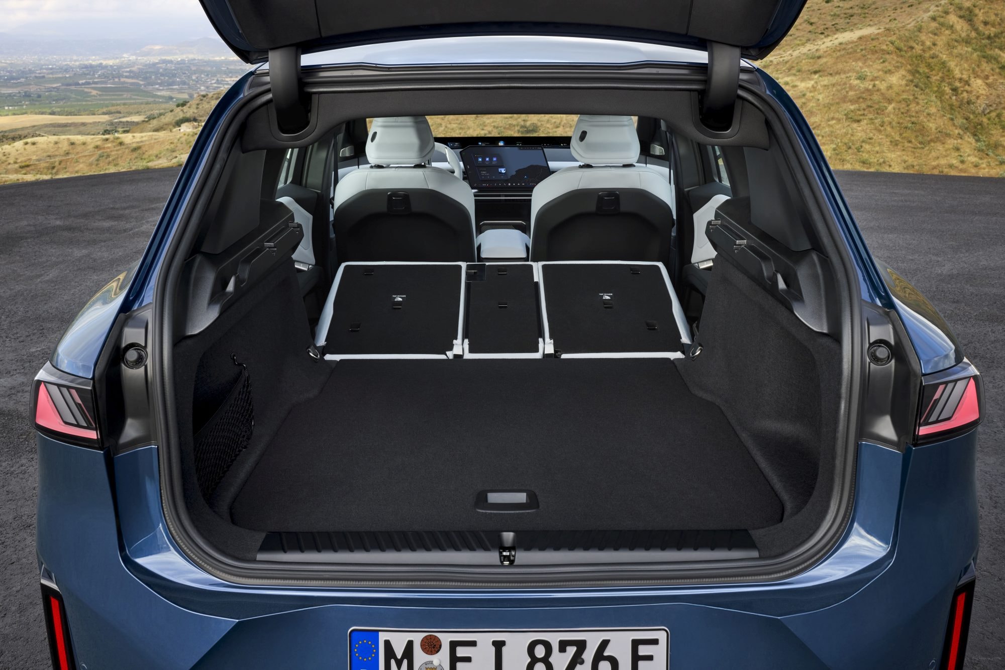 Frontal del BMW iX3 captado en una ruta despejada.