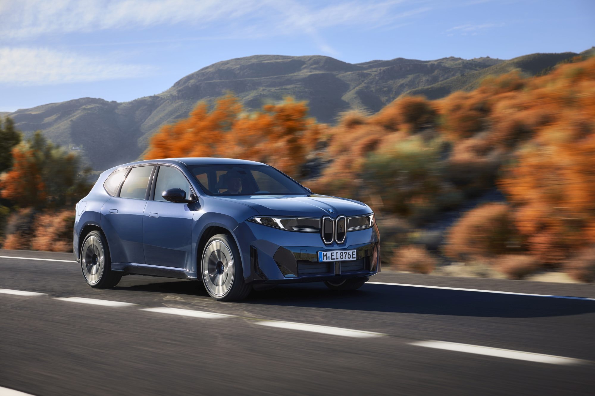 Perspectiva trasera del BMW iX3 con un paisaje árido al fondo.