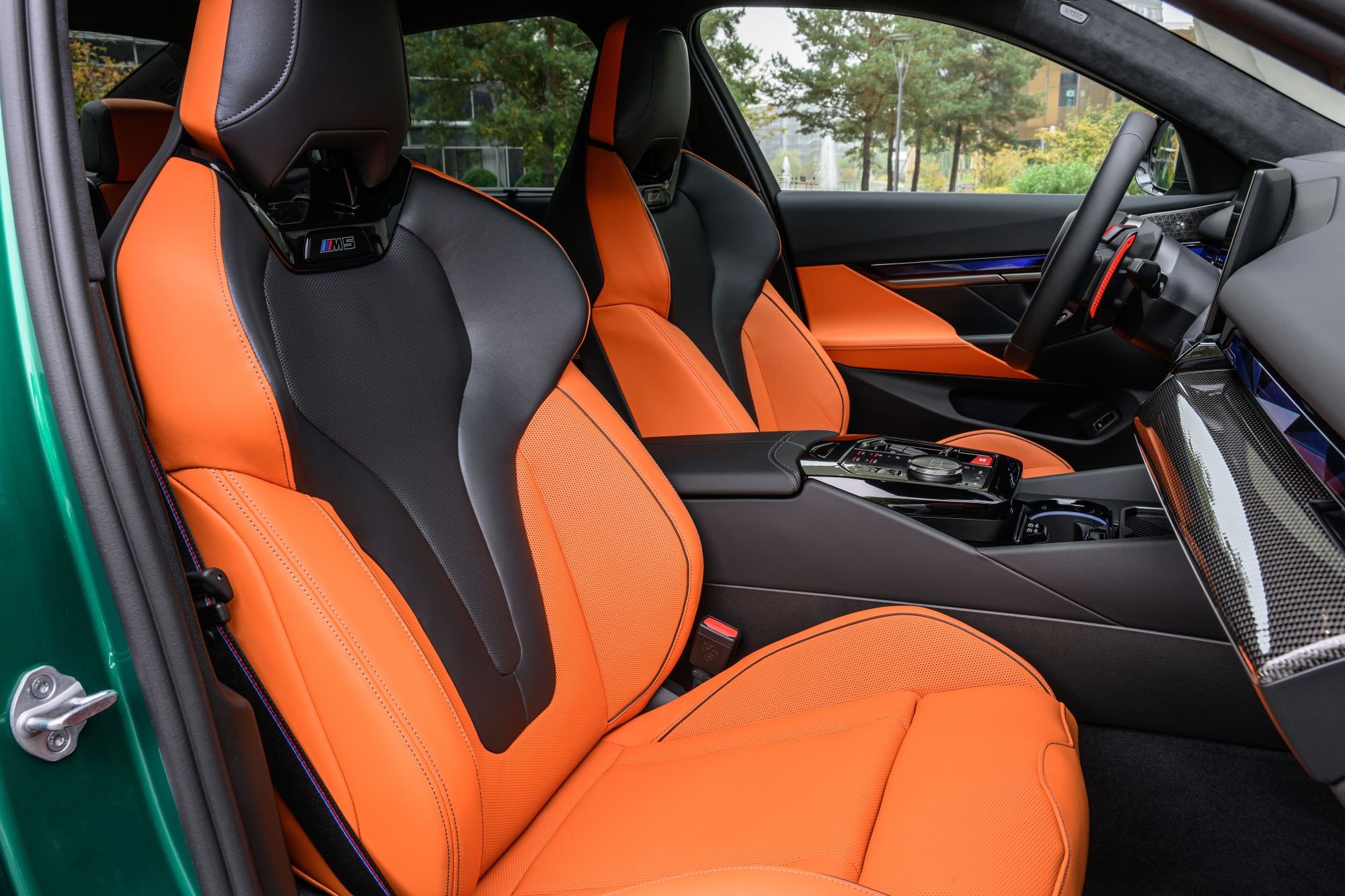 Interior del BMW M5 con asientos de cuero naranja, lujo y confort.