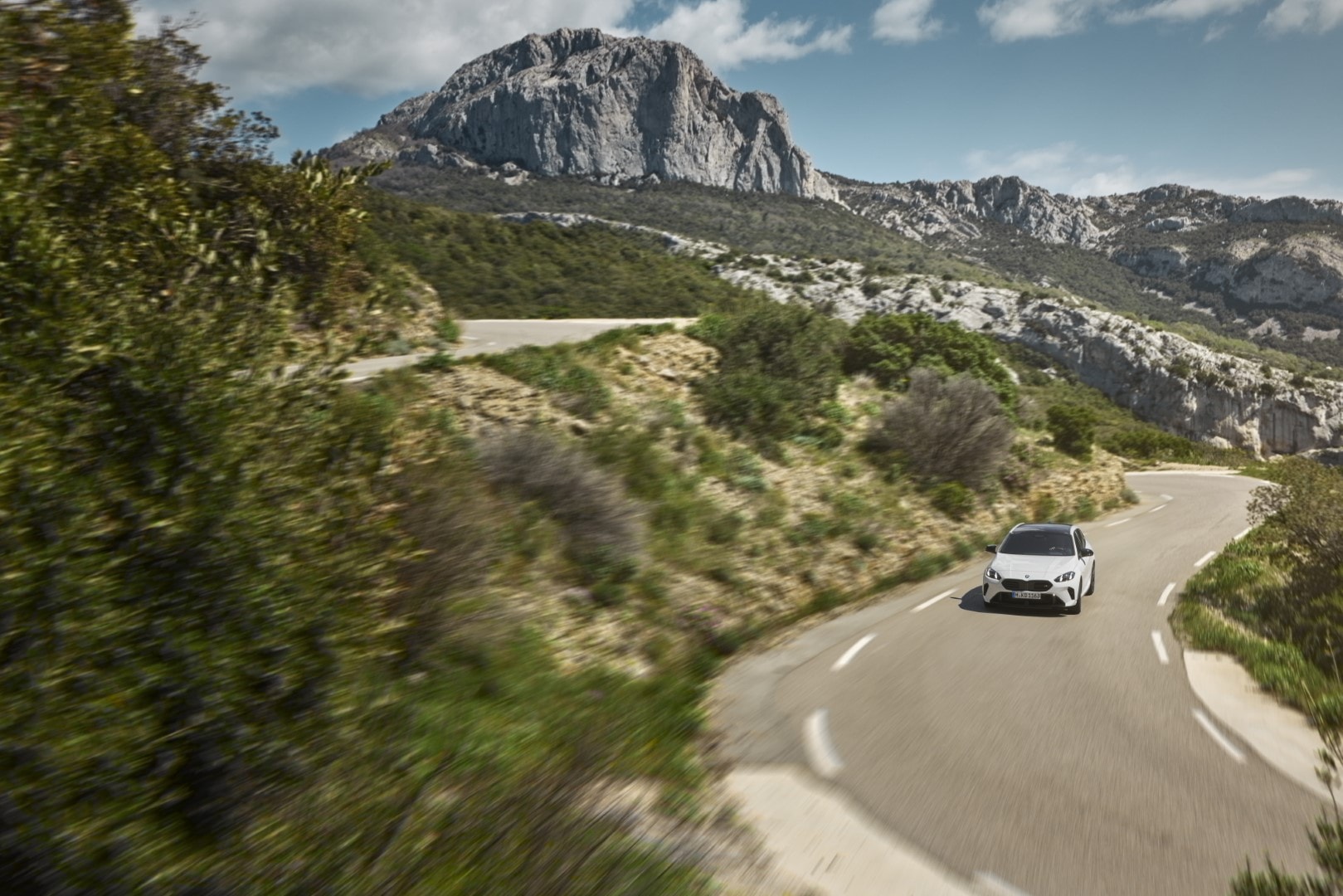 BMW Serie 1 en carretera de montaña mostrando su dinamismo y diseño frontal.