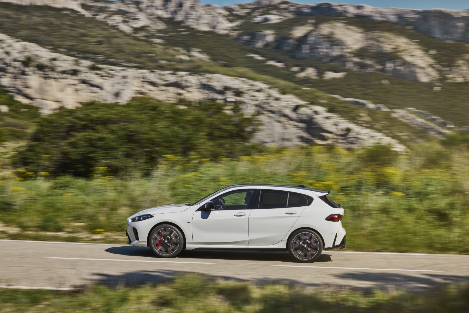 Perfil dinámico del BMW Serie 1 en carretera, resaltando su línea y llantas.