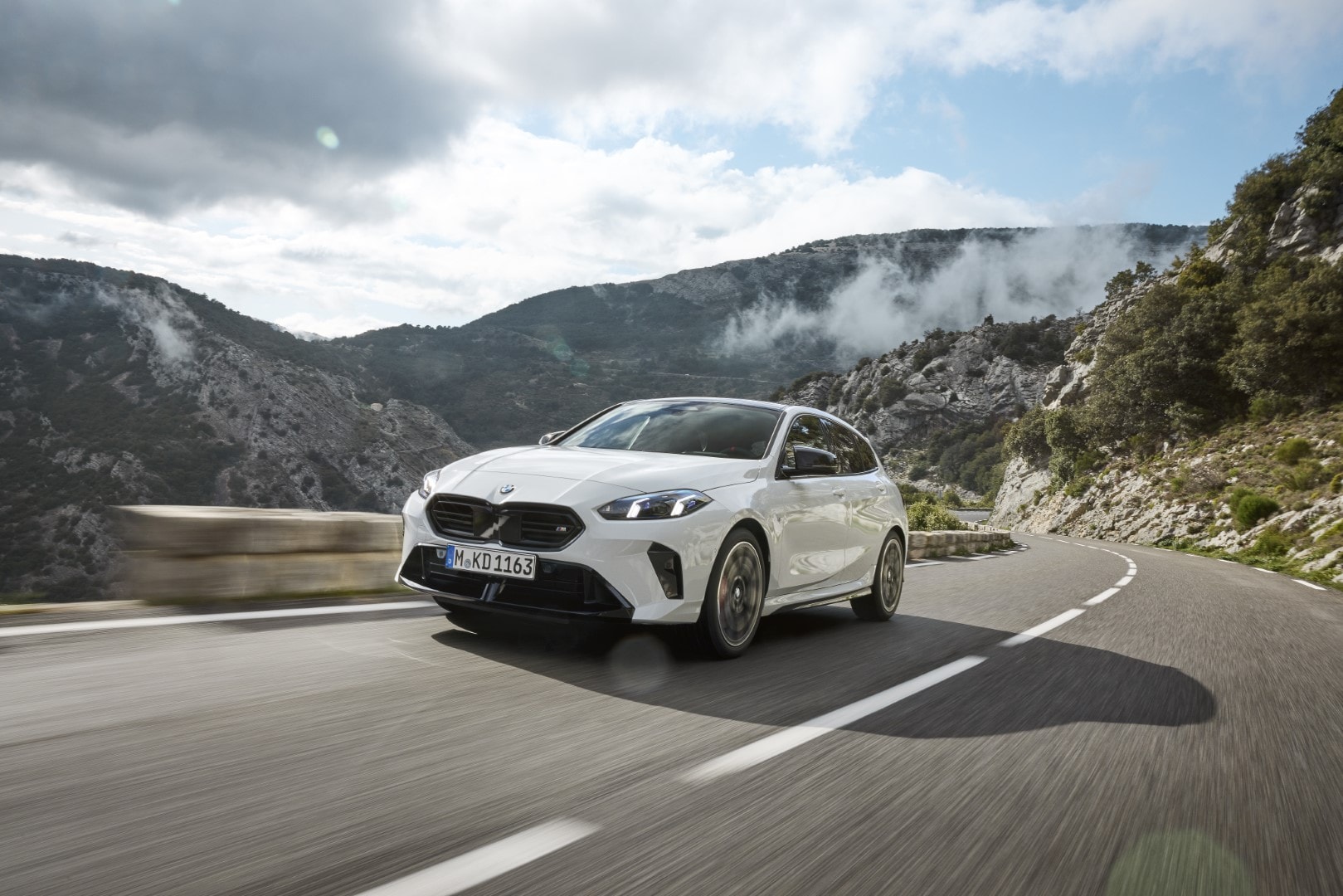 Perfil lateral del BMW Serie 1 en carretera, integración perfecta con la naturaleza.