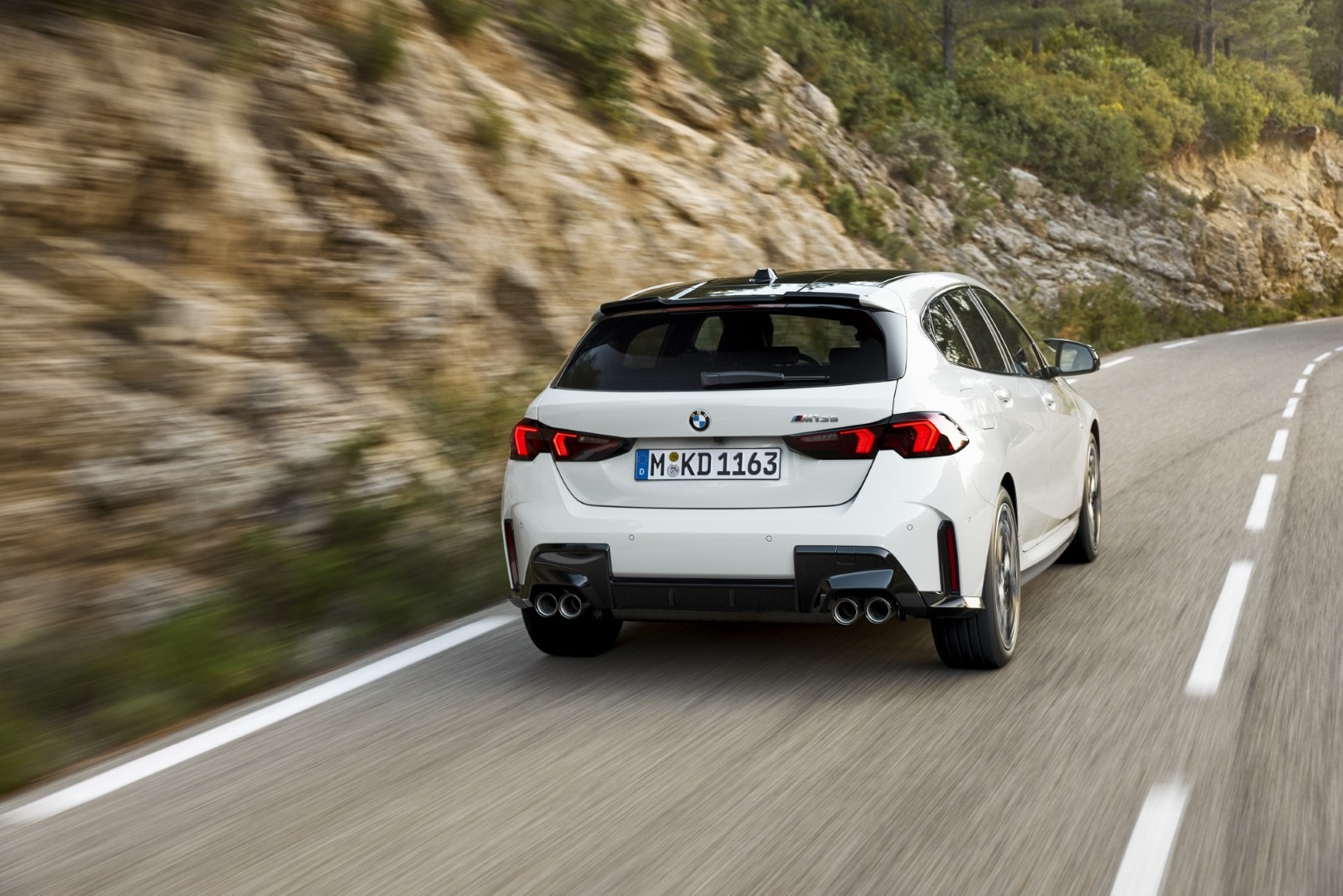 BMW Serie 1 captado desde atrás en movimiento, subrayando su silueta y performance.