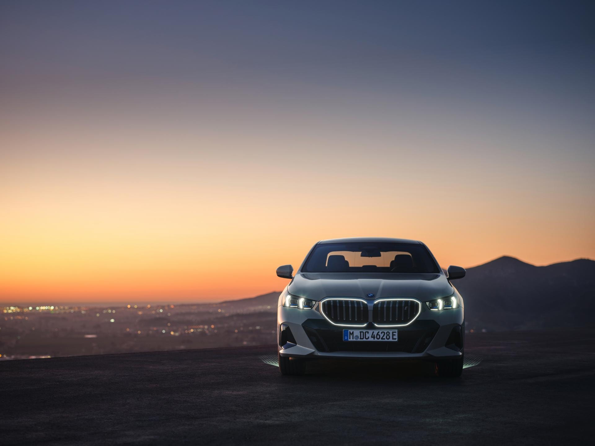 Sedán BMW Serie 5 Híbrido con frontal iluminado por el amanecer.