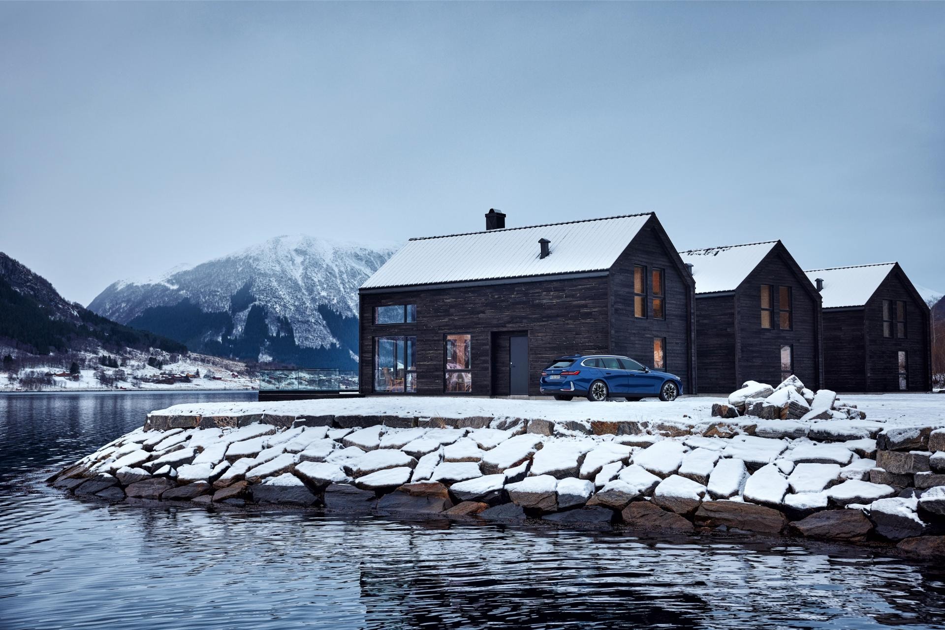 Vista lateral del BMW Serie 5 Touring aparcado junto a edificio moderno.