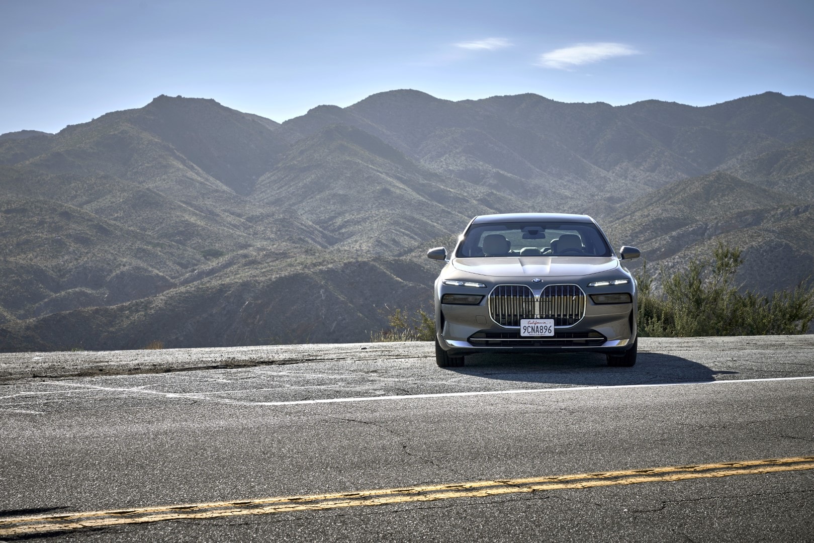Una toma frontal del BMW Serie 7 híbrido con imponente parrilla, frente a montañas.