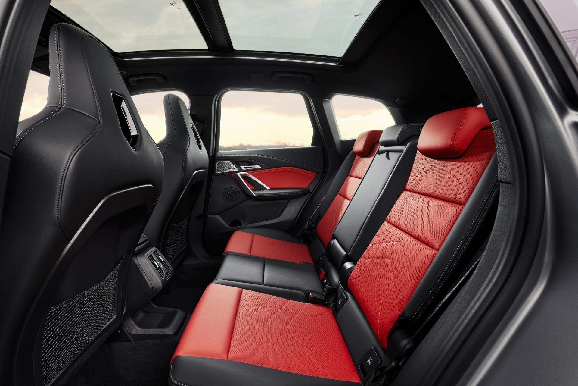 Asientos traseros en cuero rojo con amplio espacio, confort y diseño premium.