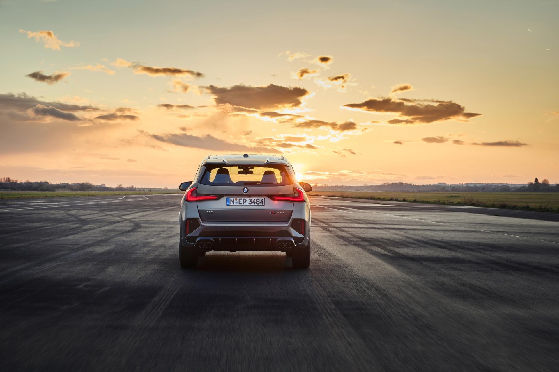 BMW X1 híbrido en carretera al atardecer, exhibiendo su diseño trasero