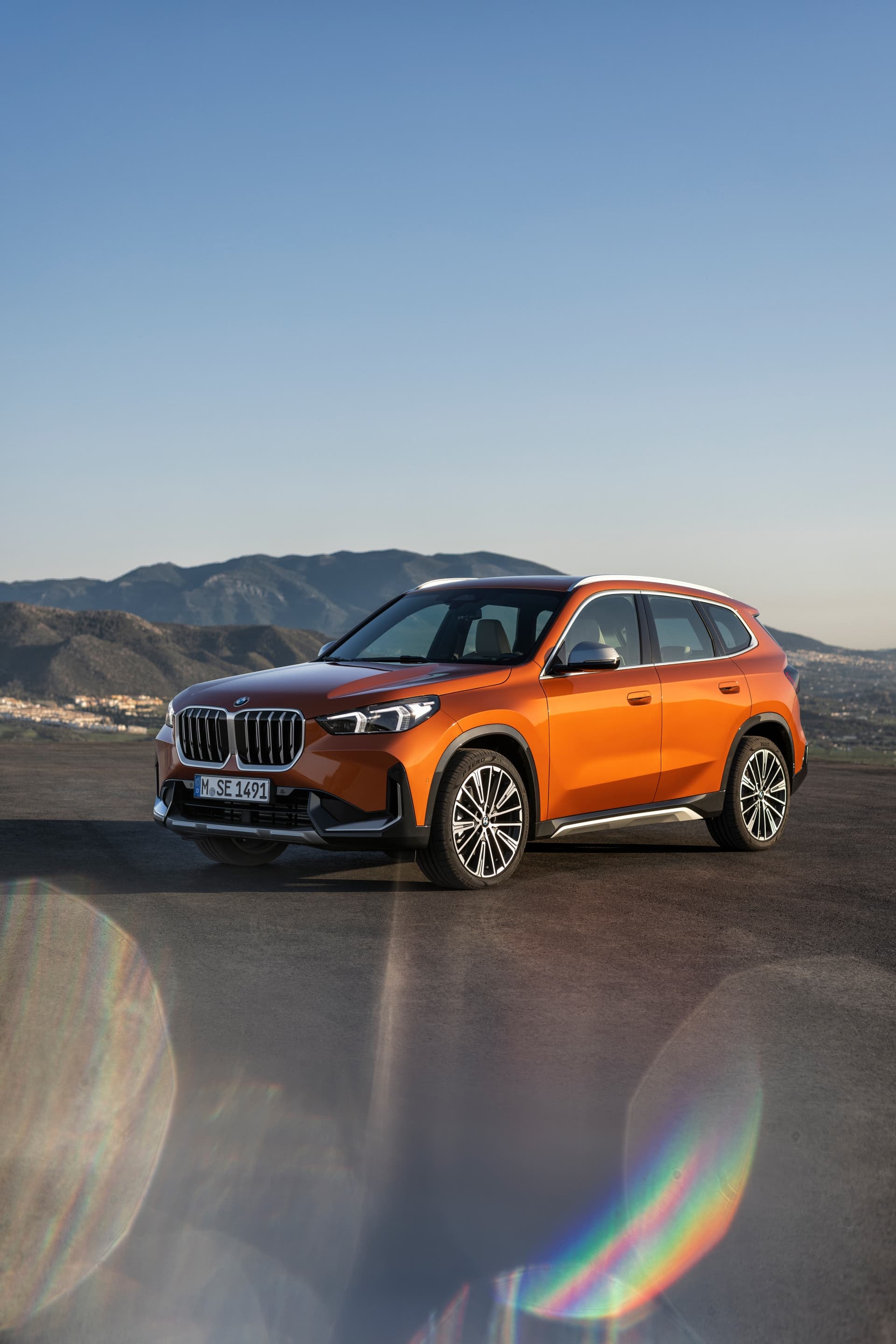 BMW X1 bajo la luz del sol, realzando el color y líneas de diseño.
