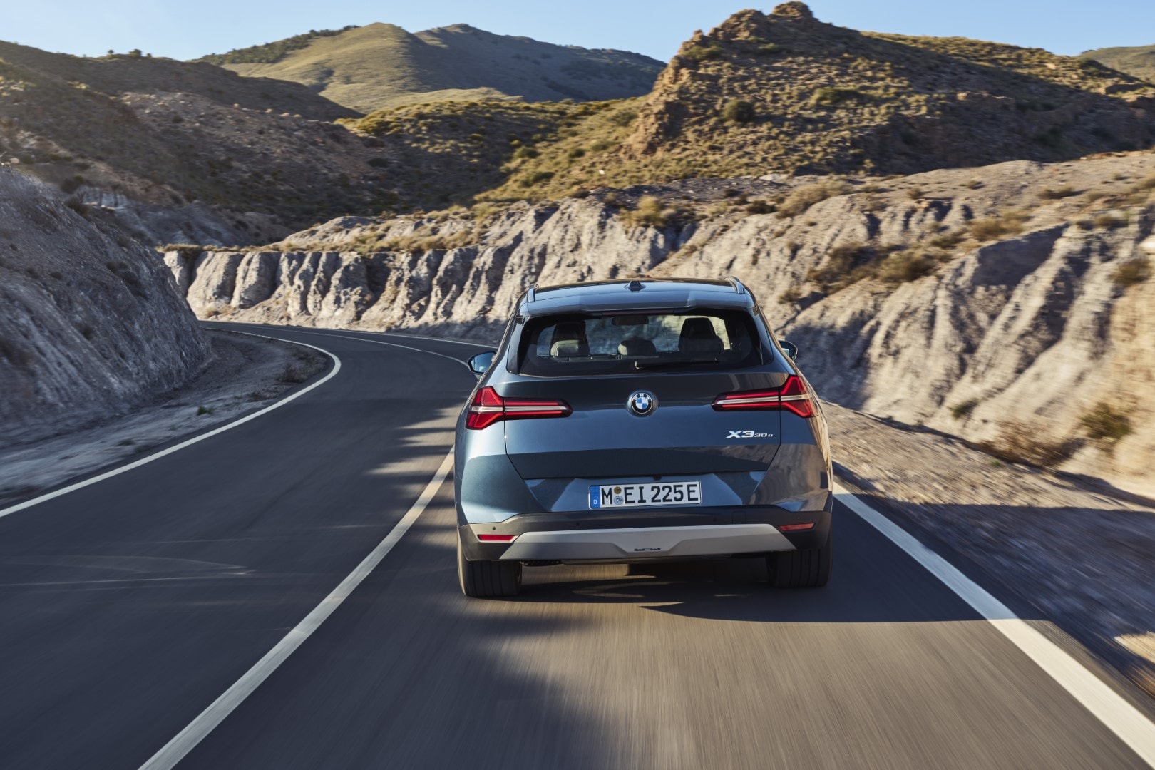 La trasera del BMW X3 híbrido en ruta, resaltando el diseño de sus pilotos y su capacidad dinámica.