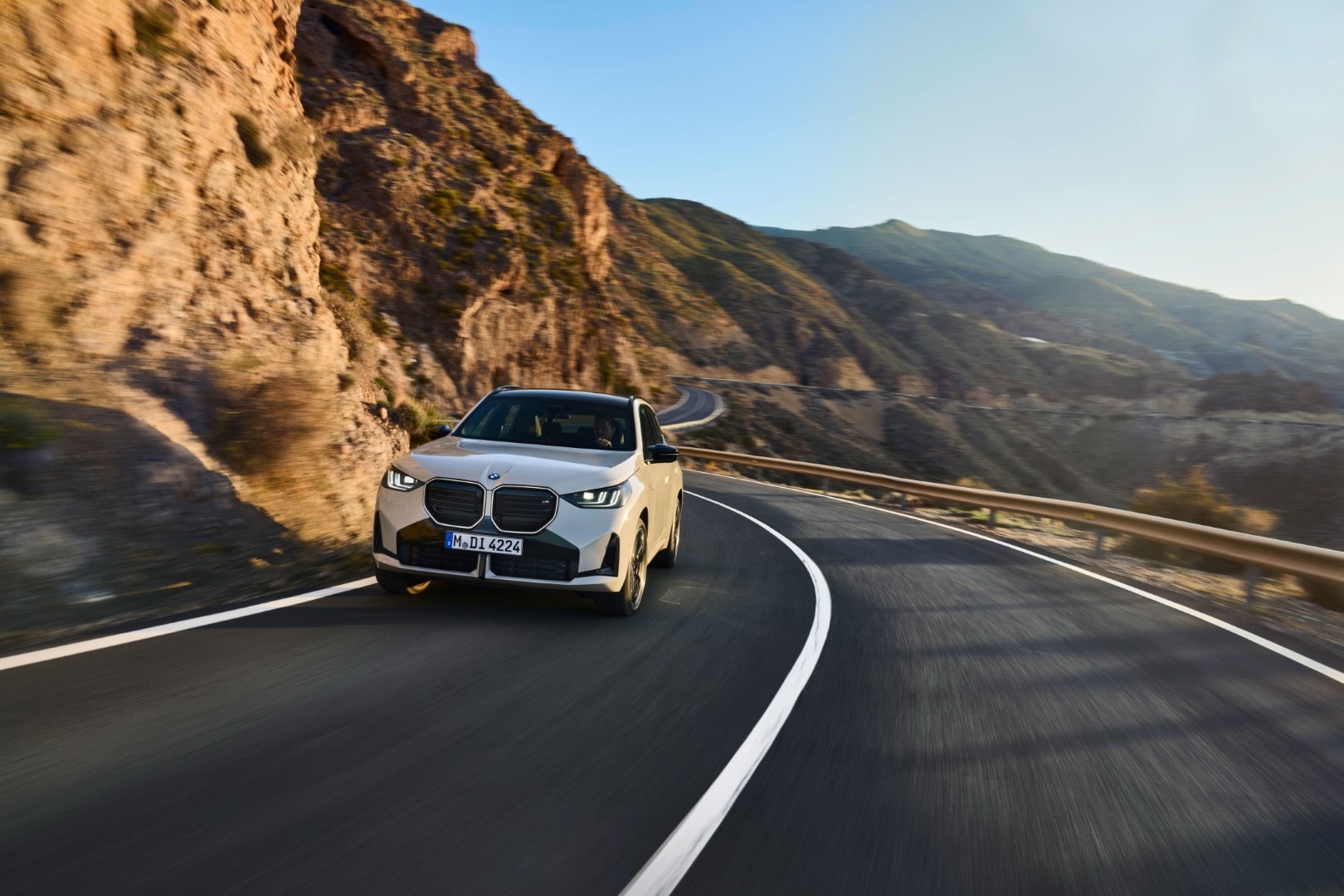 BMW X3 conduciendo en un entorno montañoso, enfatizando su capacidad en carretera.