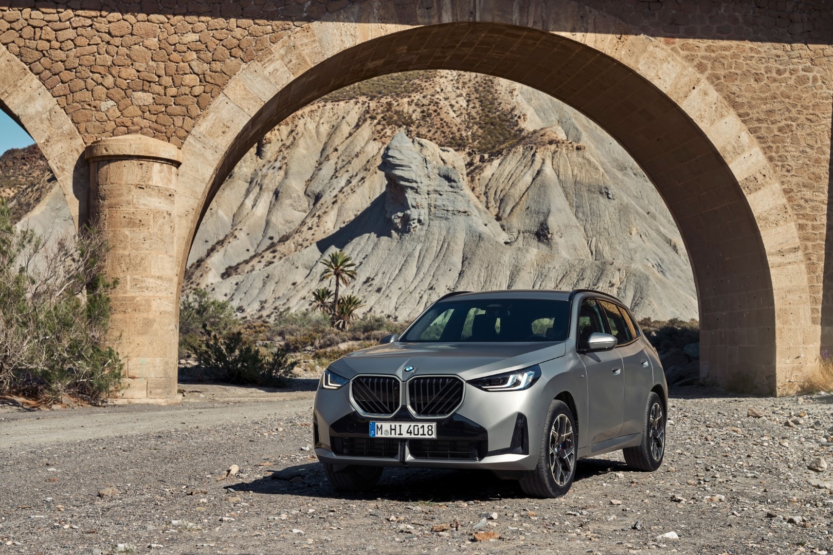 Vista delantera y lateral del BMW X3 bajo un puente de piedra.