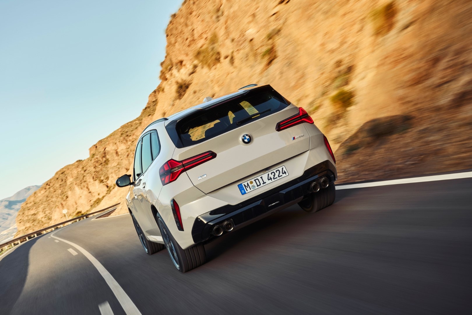 Vista trasera del BMW X3 en movimiento, resaltando su diseño y escape deportivo.