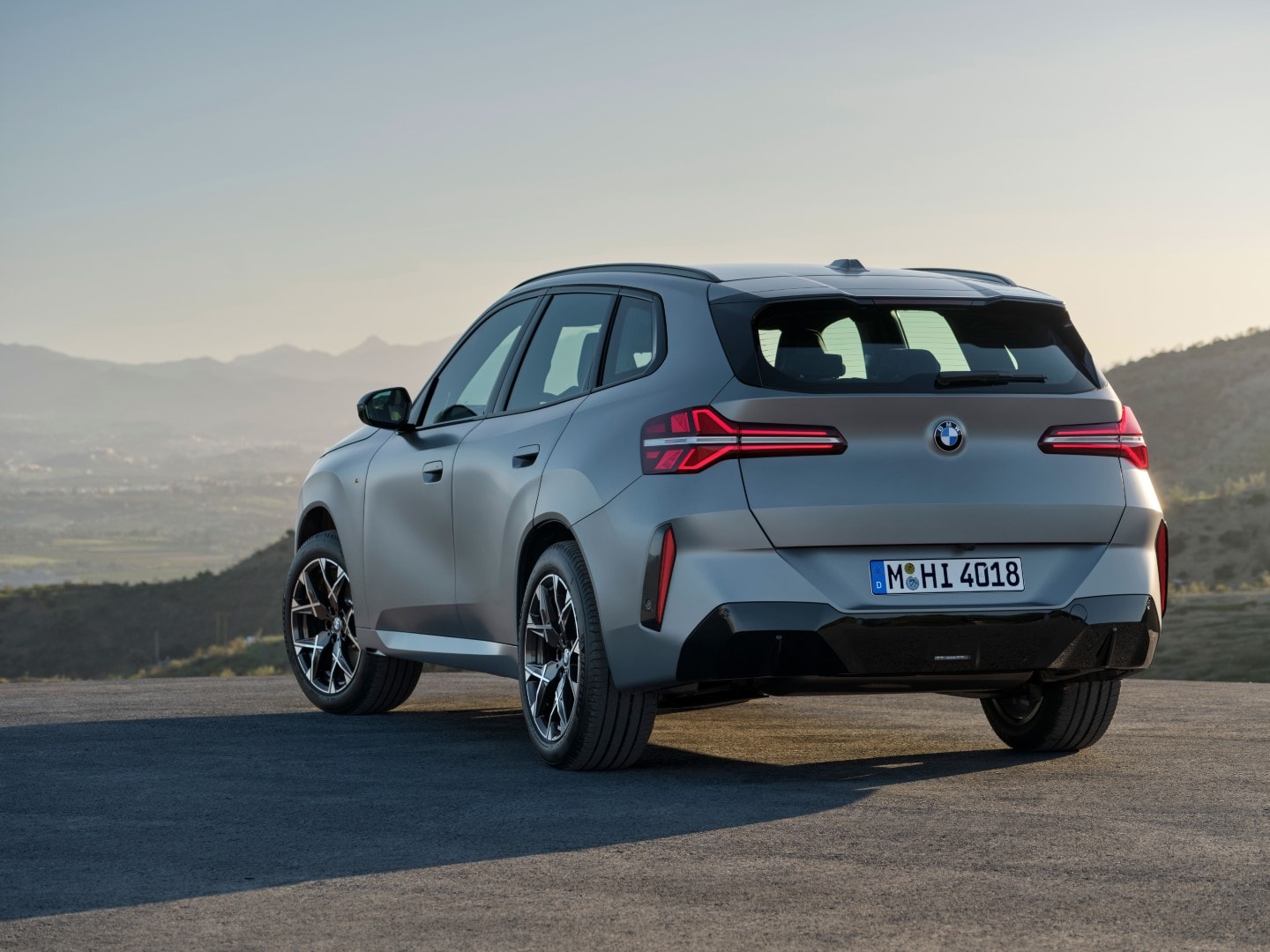 Vista trasera y lateral del BMW X3 en una carretera con paisaje montañoso.