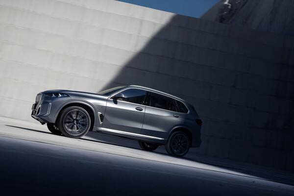Vista lateral del BMW X5 híbrido en movimiento, diseño y líneas modernas. Vista lateral del BMW X5 híbrido en movimiento, diseño y líneas modernas.