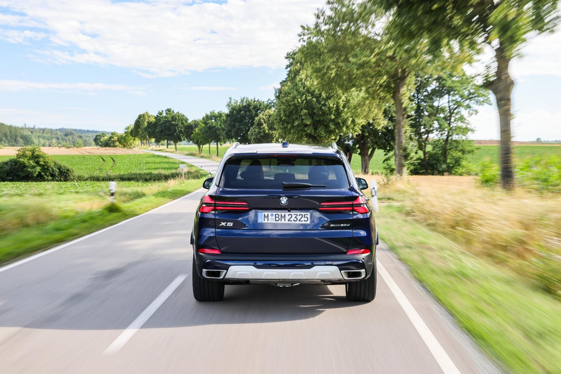 Imagen dinámica del BMW X5 Híbrido mostrando su diseño trasero en carretera.