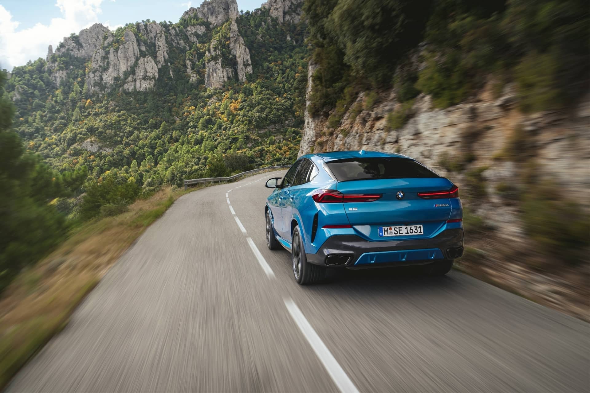 Vista dinámica trasera del BMW X6 en carretera de montaña.